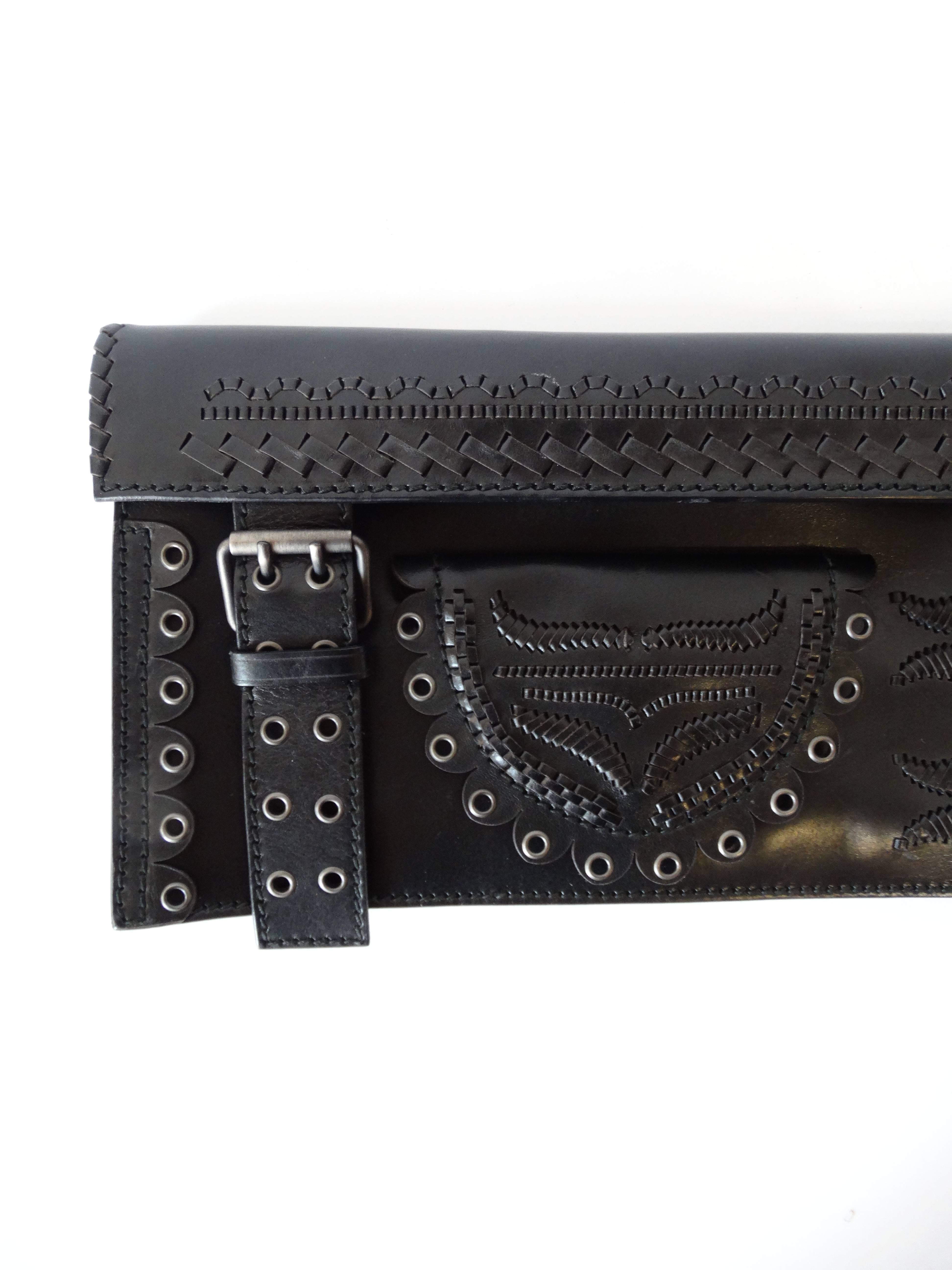 Score yourself some incredible Tom Ford for Yves Saint Laurent with our clutch from the Fall/Winter 2001 collection! Long rectangular black leather clutch with silver grommet details. Braided, woven and cut outs throughout the leather. Unique