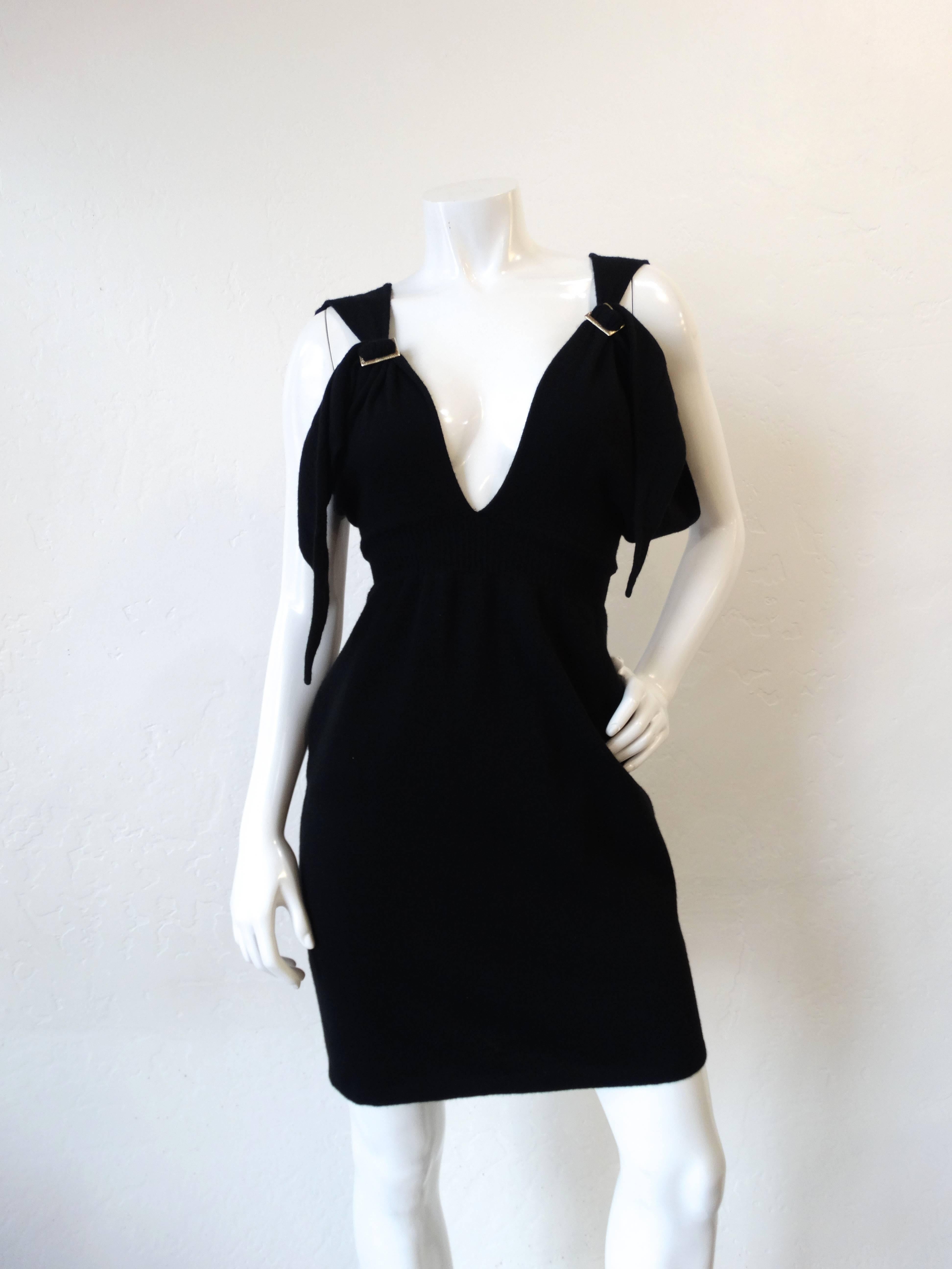 Classy meets sexy in our incredible knit Chanel dress from 2009! Solid black stretch knit mini dress with sexy plunge neckline. Two silver Chanel buckle details on either of the straps. Matching belt is adjustable for a perfectly cinched fit and is