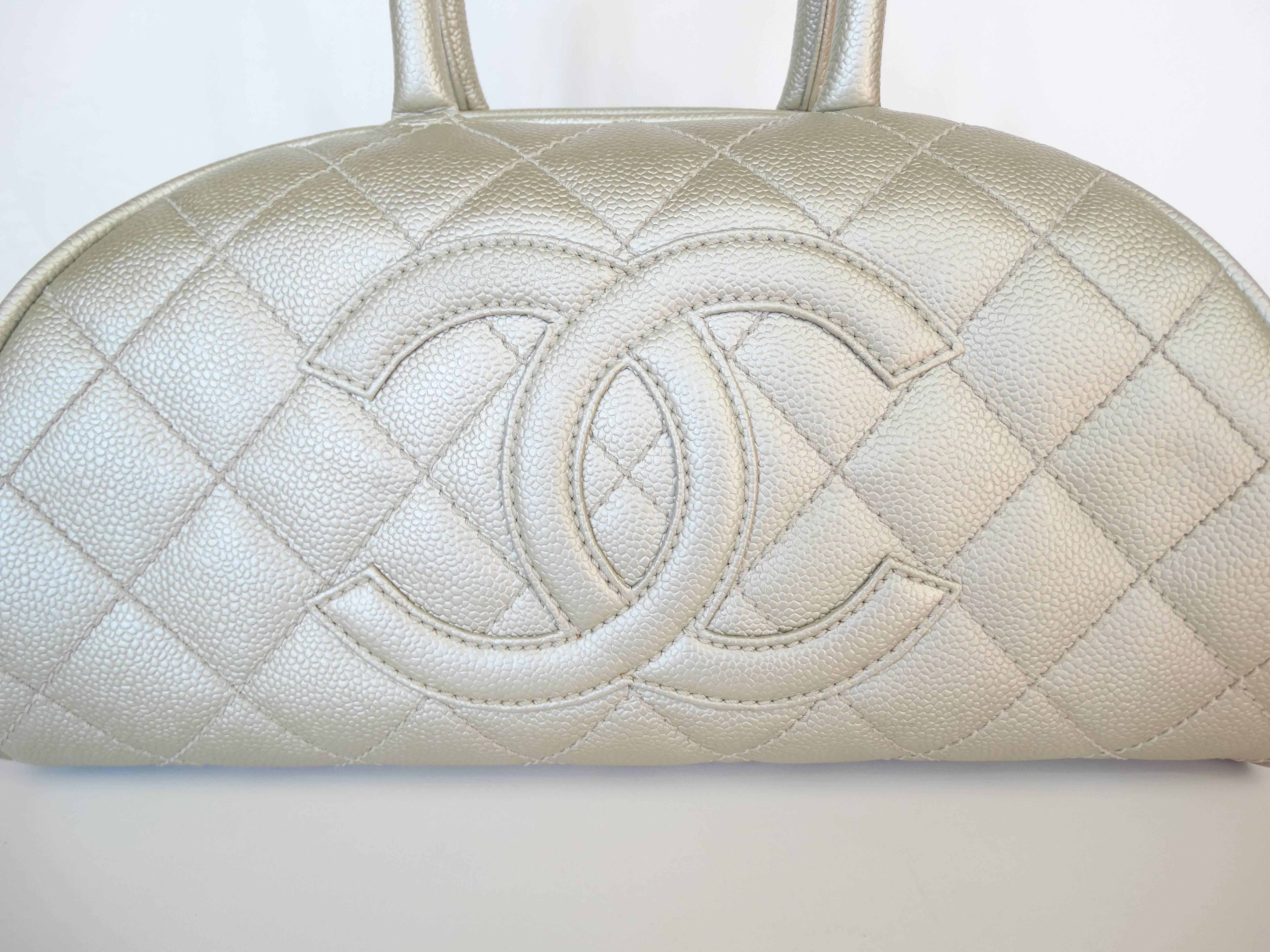The most adorable Chanel bowler bag! Made of a silver toned metallic caviar leather with signature Chanel quilting and CC logo on the front. Quilting continues onto the back of the bag. Lampo zipper zips open from the top to reveal fully lined