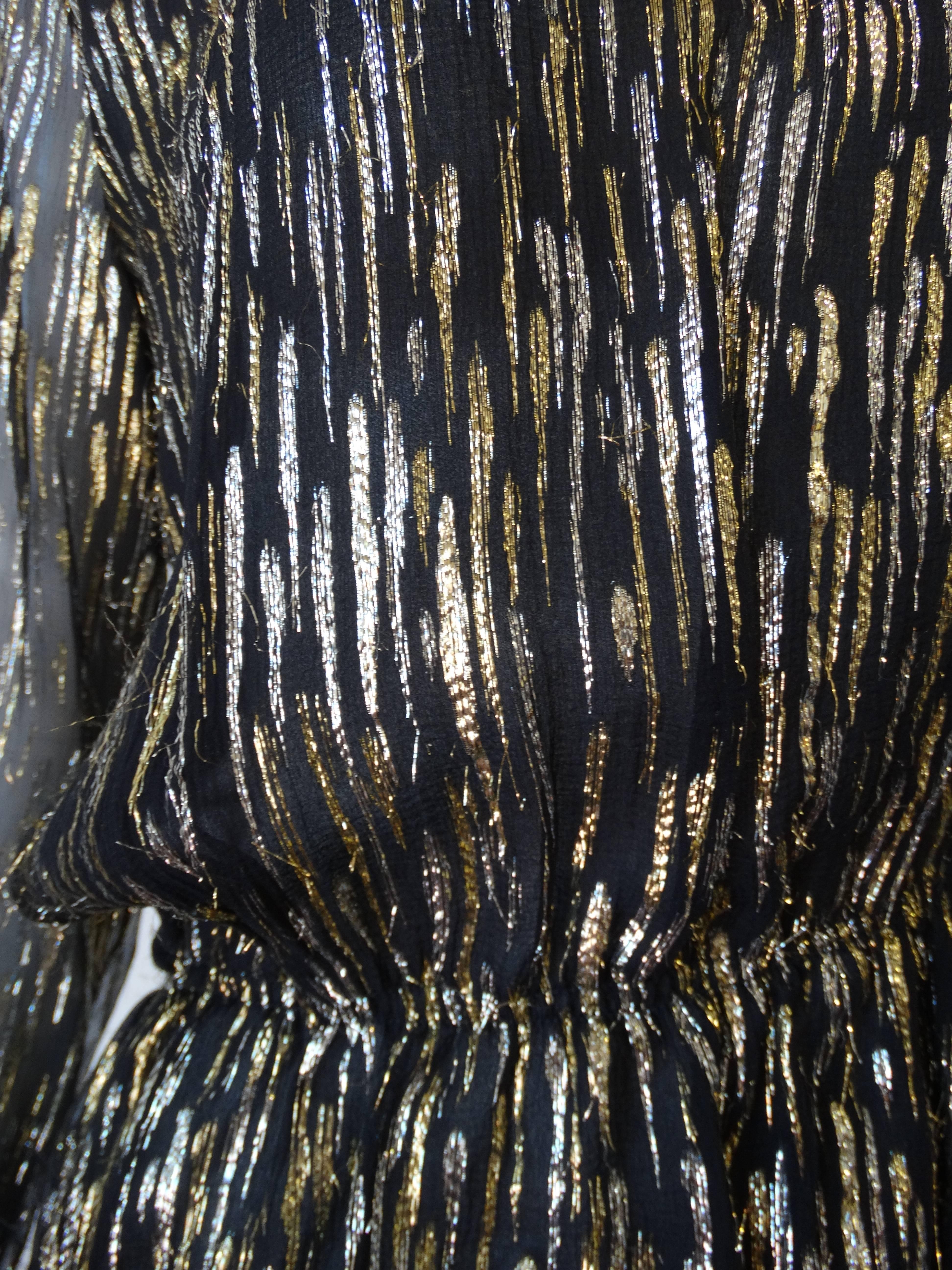 Step out with shine in our incredible 1980s blouse from Chanel's ready to wear line- Chanel Creations. Made of a sheer black fabric interwoven with strips of gold and silver metallic threads. Peplum like fit with elasticized cinched waistline.