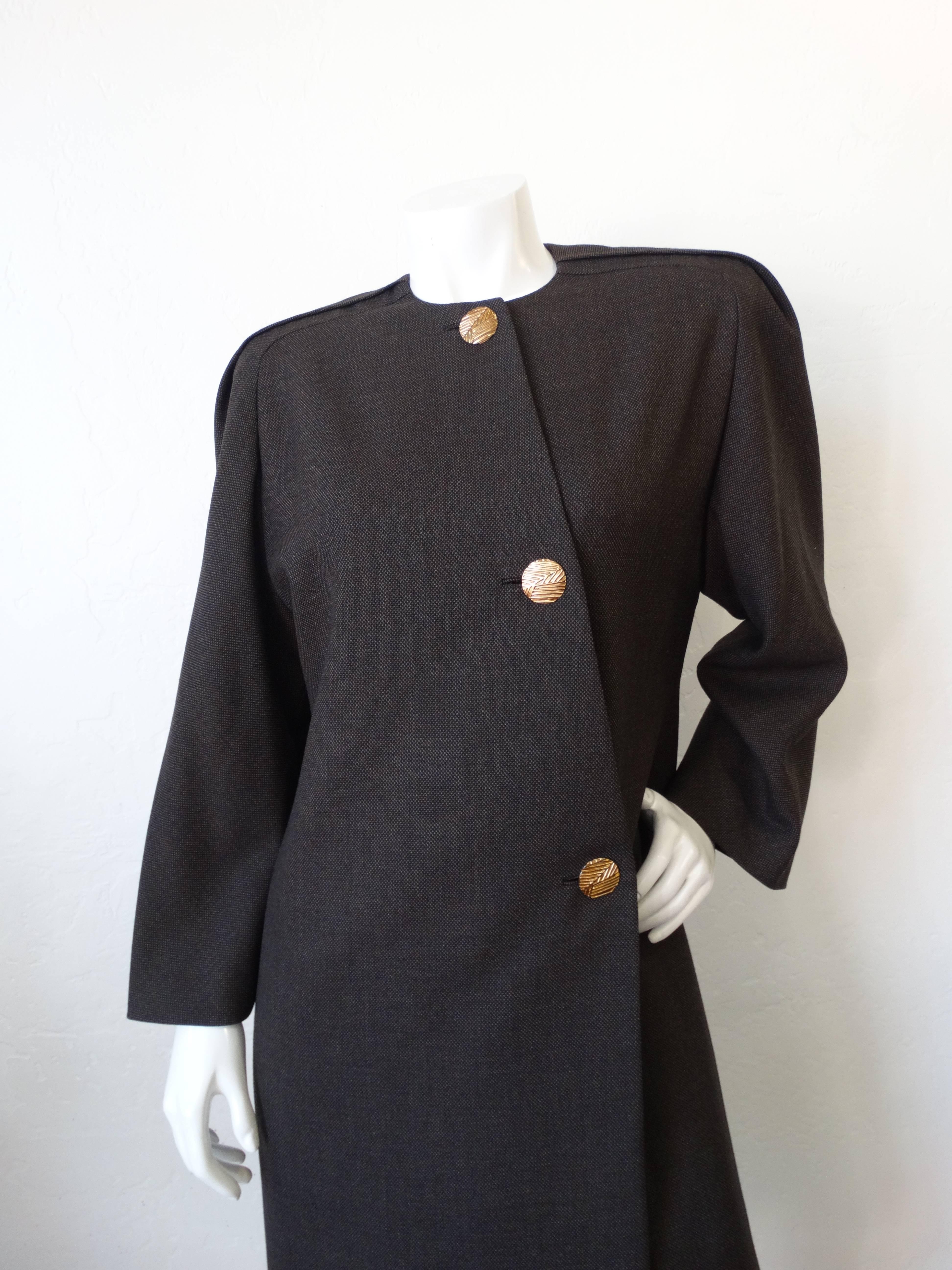 This piece is giving us vintage meets Jacquemus vibes! This incredible 1980s Galanos piece can be worn open as a coat or closed as a dress- it's up to you! Dark cool grey fabric with gold oversized buttons down the front. Asymmetrical button