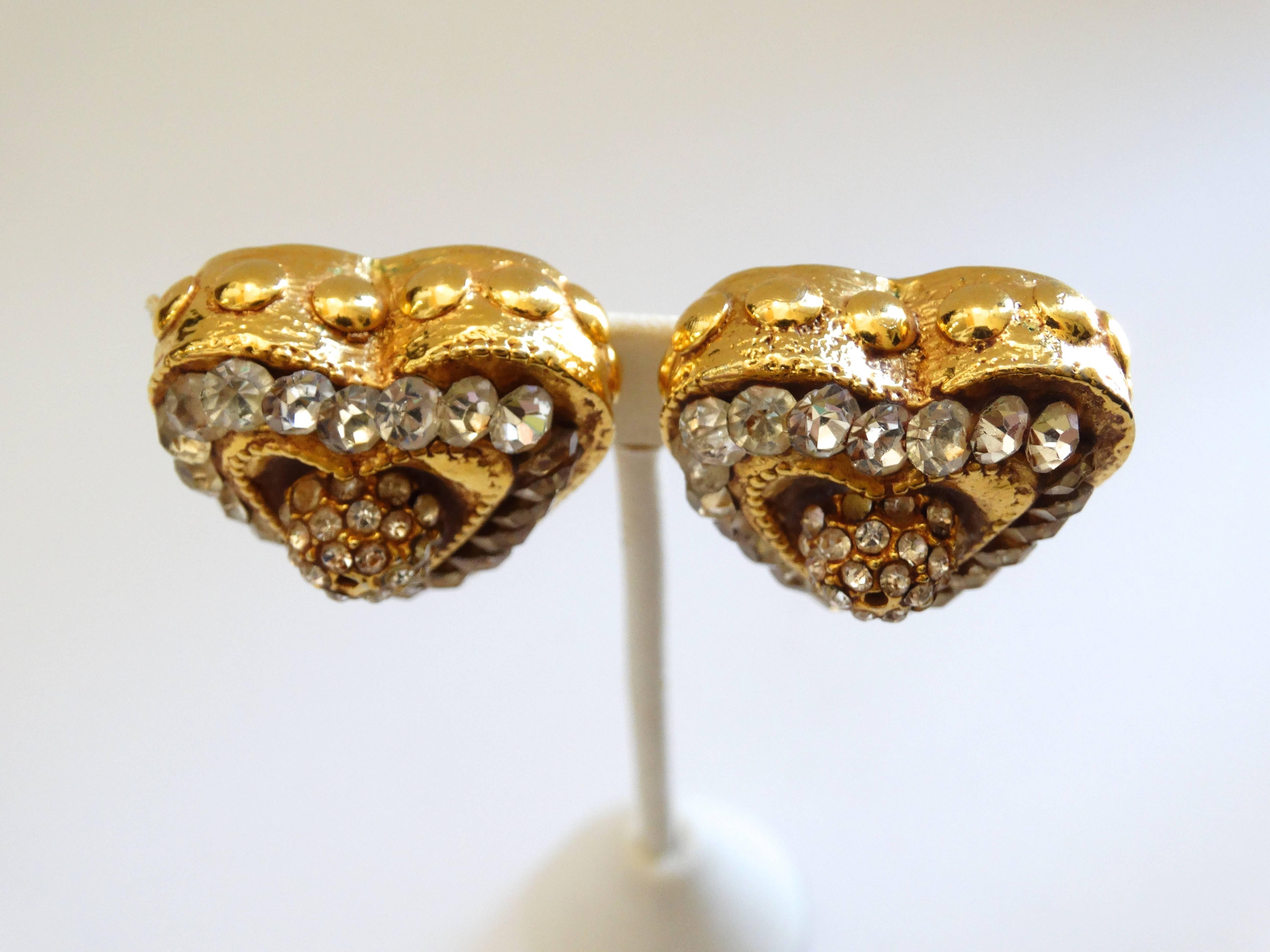Dazzle them in our amazing 1980s heart shaped earrings from Kalinger Paris! Cast out of a quality gold metal and accented with rhinestones all around the perimeter of the heart. Rhinestone encrusted ball in the center. Clip on backs. Signed Kalinger