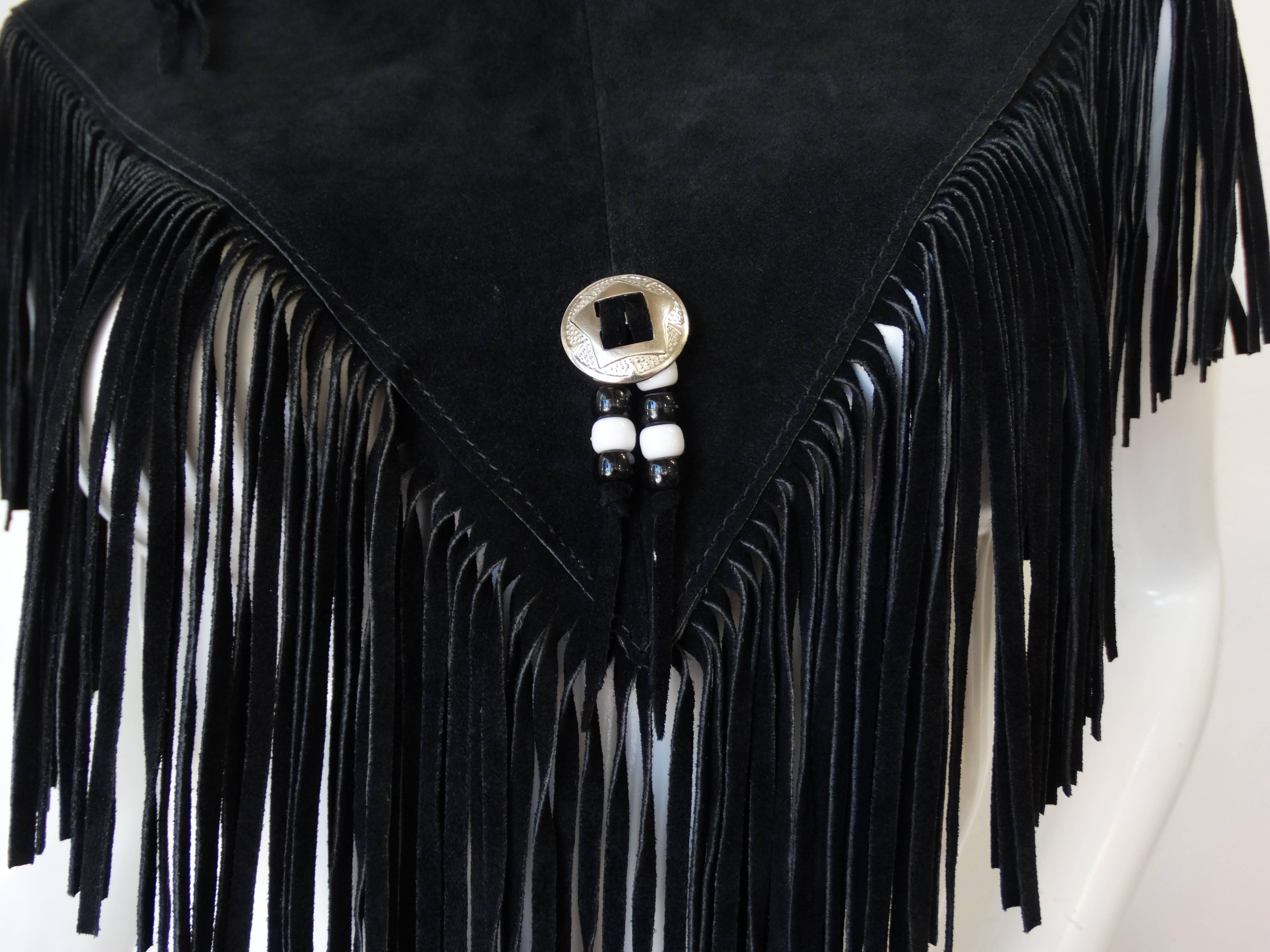The perfect piece for your upcoming festival wardrobe! Made of a soft black suede. Yoke silhouette- sits comfortably on the shoulders. Long fringe trim, accented with silver concho charms and black and white beads. Pair with a bralette and some