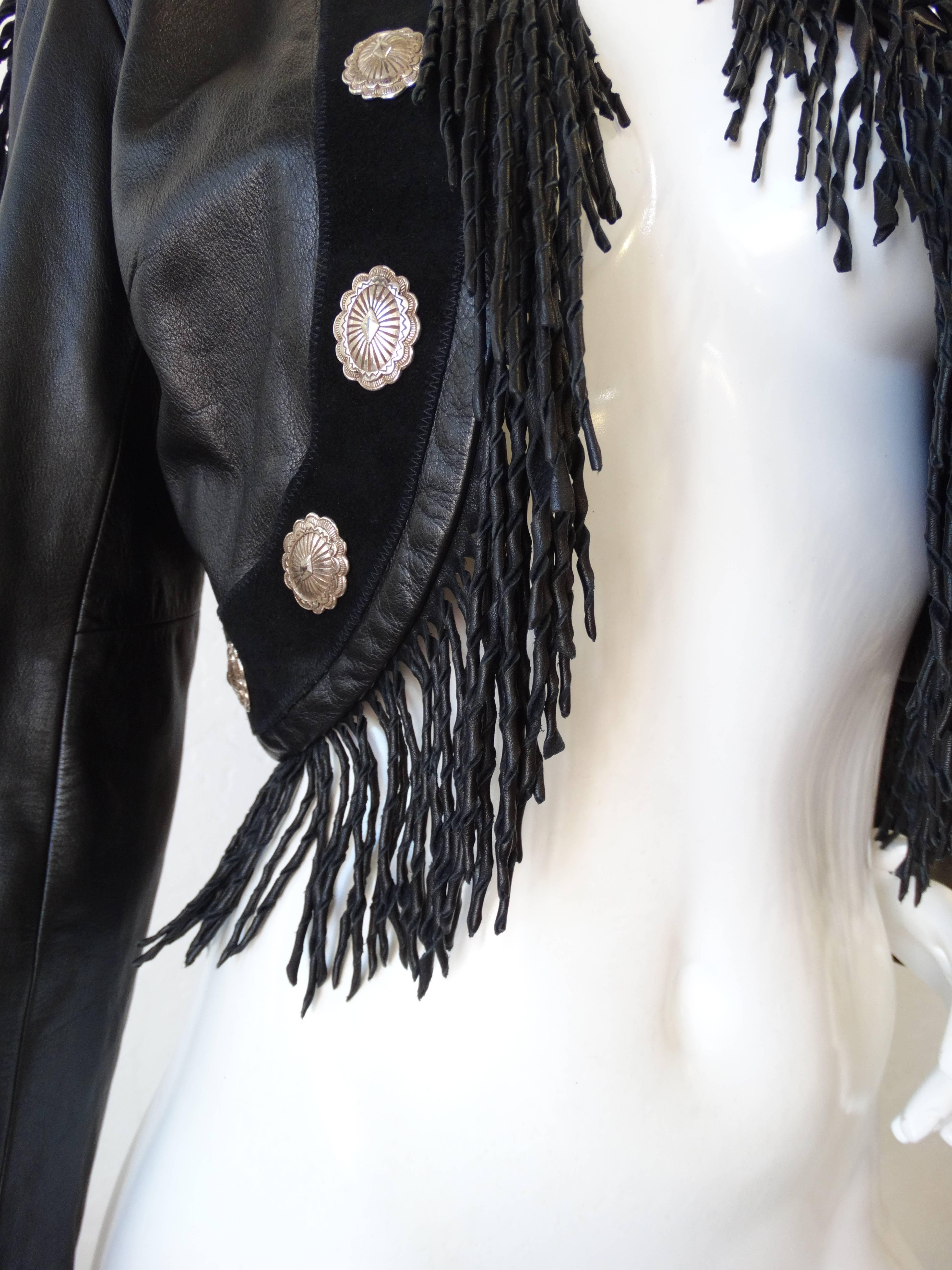 Rock our favorite trend of the 1980s- the fringe leather jacket! Made of a super soft black leather with matching twisted fringe all along the sleeves. Black suede trim on the body of the jacket, with silver concho charms which give this piece a