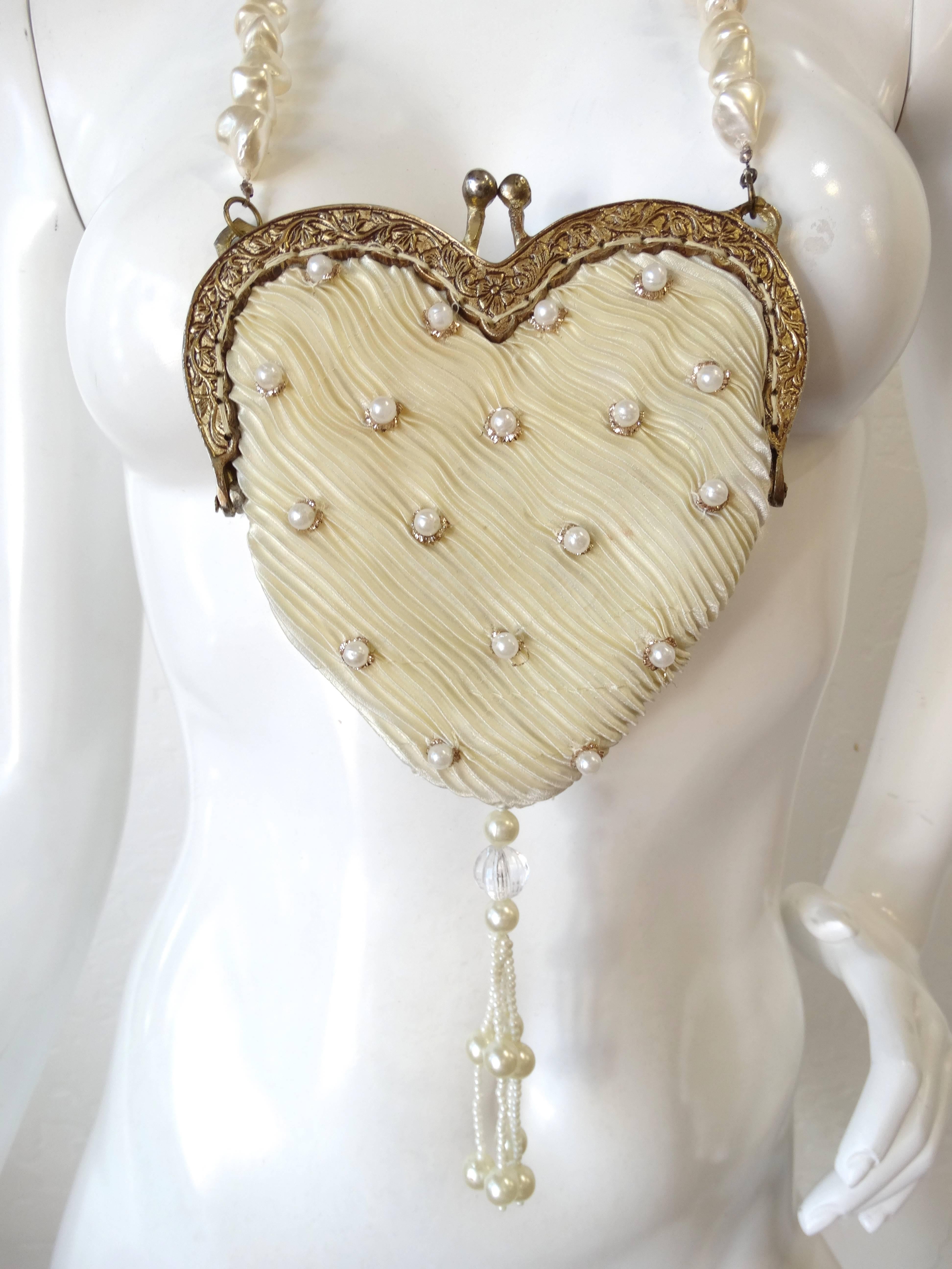 Amazing 1980s heart shaped bag with pearl strap! Micro-pleated cream colored fabric accented with gold thread and pearl beads throughout. Heart shaped construction with metal kiss lock frame. Long freshwater pearl strand strap. Wear around the neck