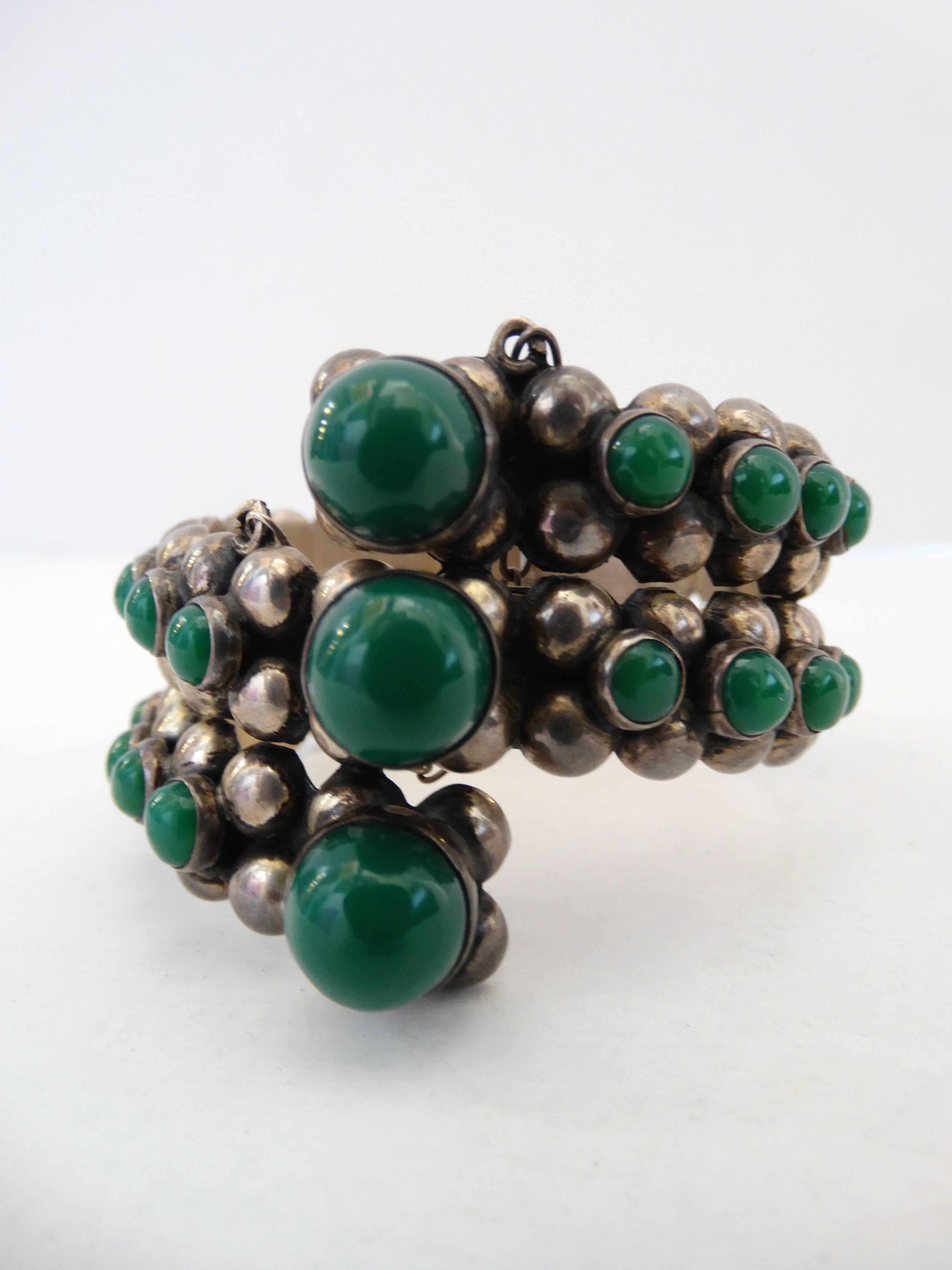 Incredible mid century silver cuff from Gonzalo Moreno! Solid sterling silver metal in a bead like pattern, accented with rows of polished green jade orbs. Hinge closure clicks open, has a silver chain to hold it in place. Signed at the back with