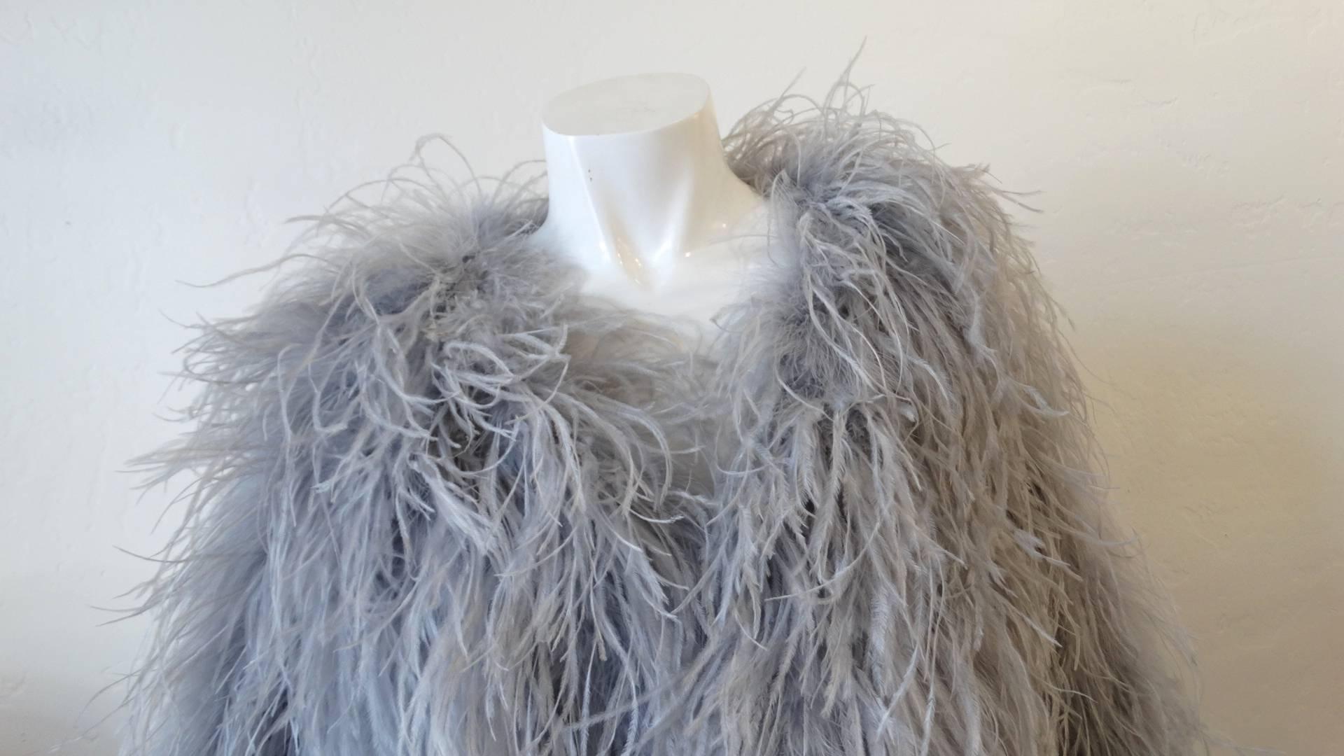 Channel your inner rockstar with our amazing grey feathered jacket from 1970s clothing label Biba! Made of a grey satin shell and completely covered with long, wispy feathers. Long sleeved fit with cropped length. Hook and eye closures up the front.