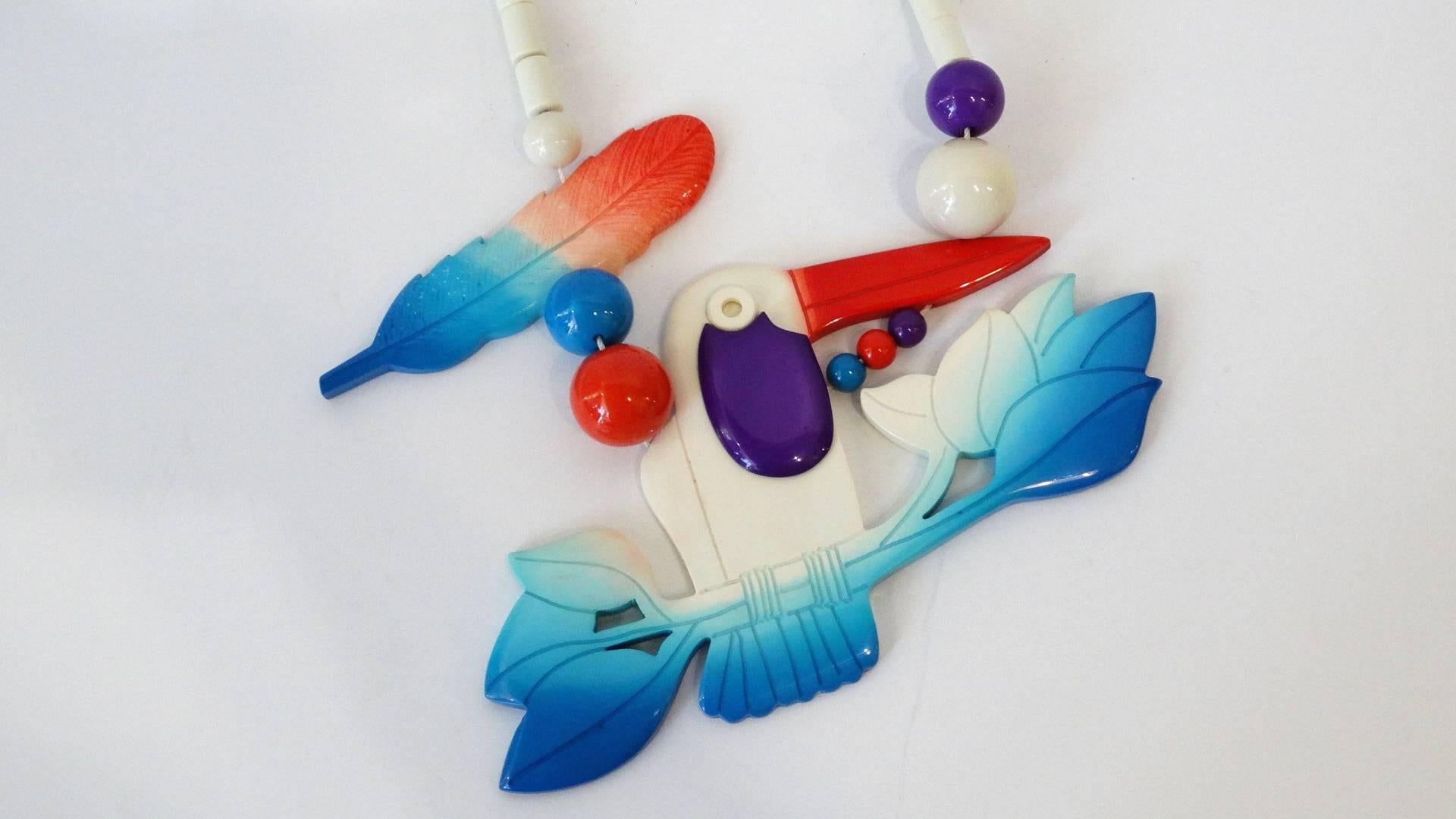Add some whimsy to your wardrobe with our amazing 1980s Isadora Paris exotic bird necklace! Crafted of a quality bakelite material in a unique red white and blue ombre color way. Oversized toucan charm at the middle with a feather charm on the side.