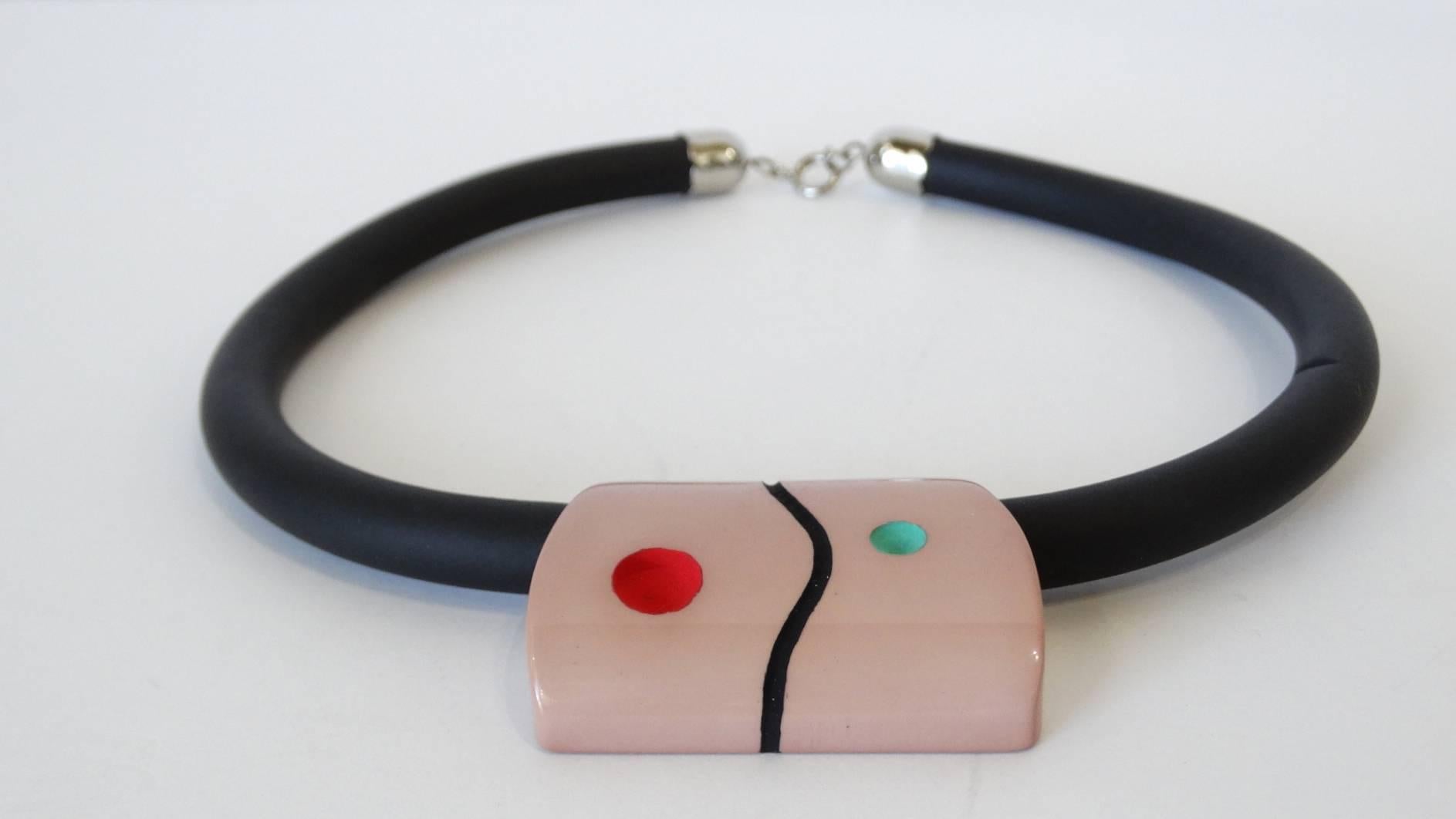 Vous avez le sens de l'avant-garde avec notre collier ras de cou Guillemette L'Hoir des années 1970 ! Bracelet noir caoutchouté avec charme minimaliste couleur chair au centre, fabriqué dans la matière Galalith, signature de Guillemette. Fermeture à