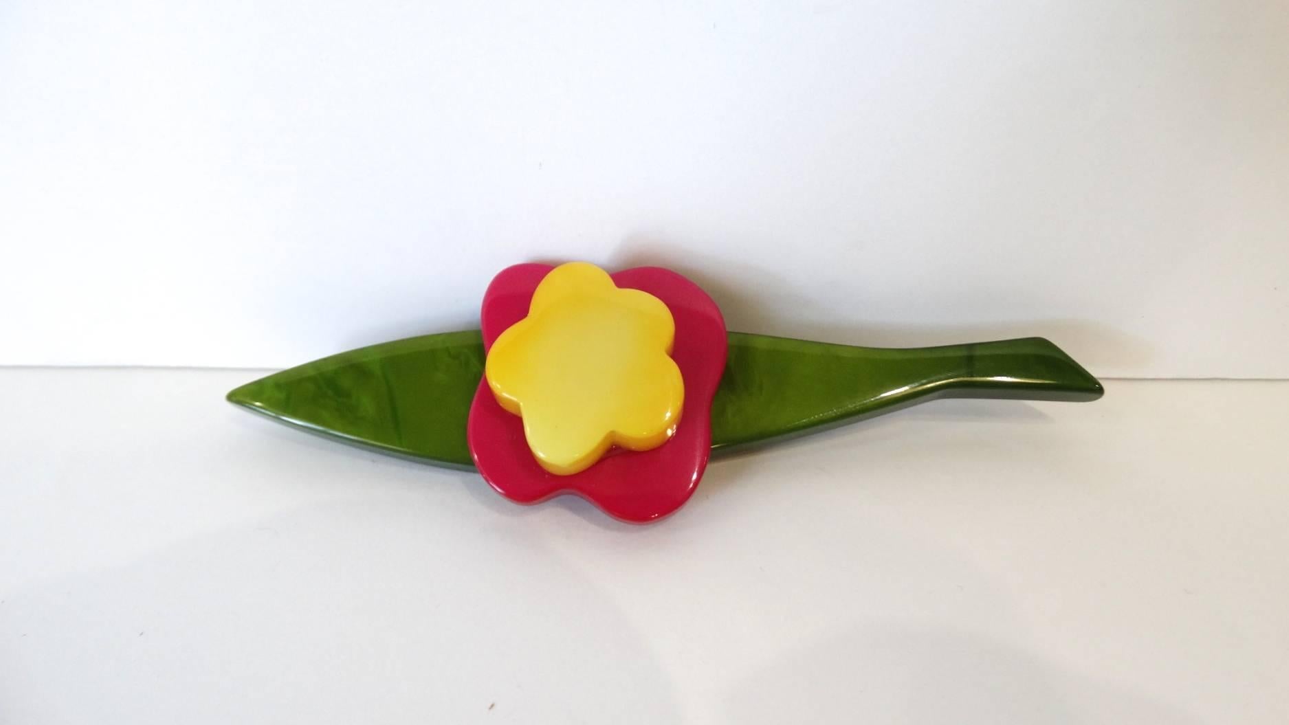 70's flower brooch from jewelry designer Marie Christine Pavone! Flower made from pink, yellow and green celluiod. Pin back, signed Pavone. 

Measures 4.5in long, flower accent is about 1x1in.