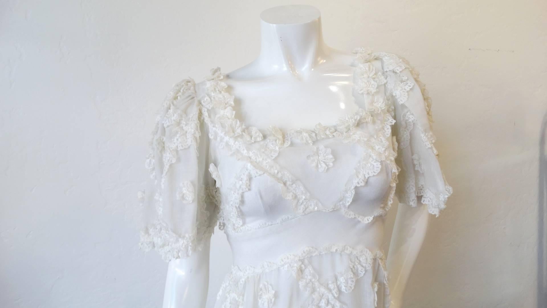 The most adorable cream lace ruffle maxi dress from the 1970s! White cotton fabric with ruffled lace stitched in a diamond pattern. Flattering empire waistline with puffed sleeves. Zips up the back. This dress measures 30