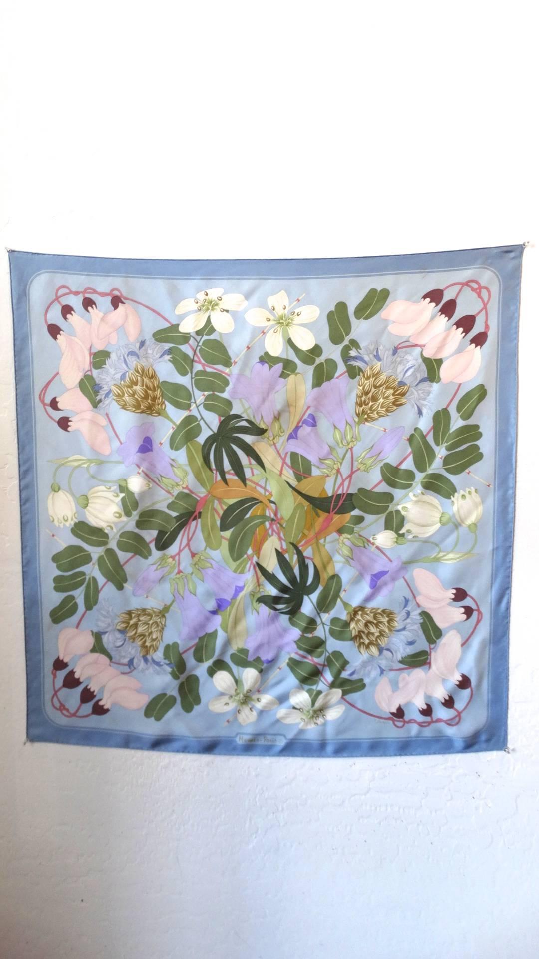 The most amazing 1983 Flora Graeca Hermes Scarf designed & signed by Niki Goulandris. A pastel blue background with a darker blue trim is complemented by a collection of purple, white and pink flowers along with greenery to create an exquisite