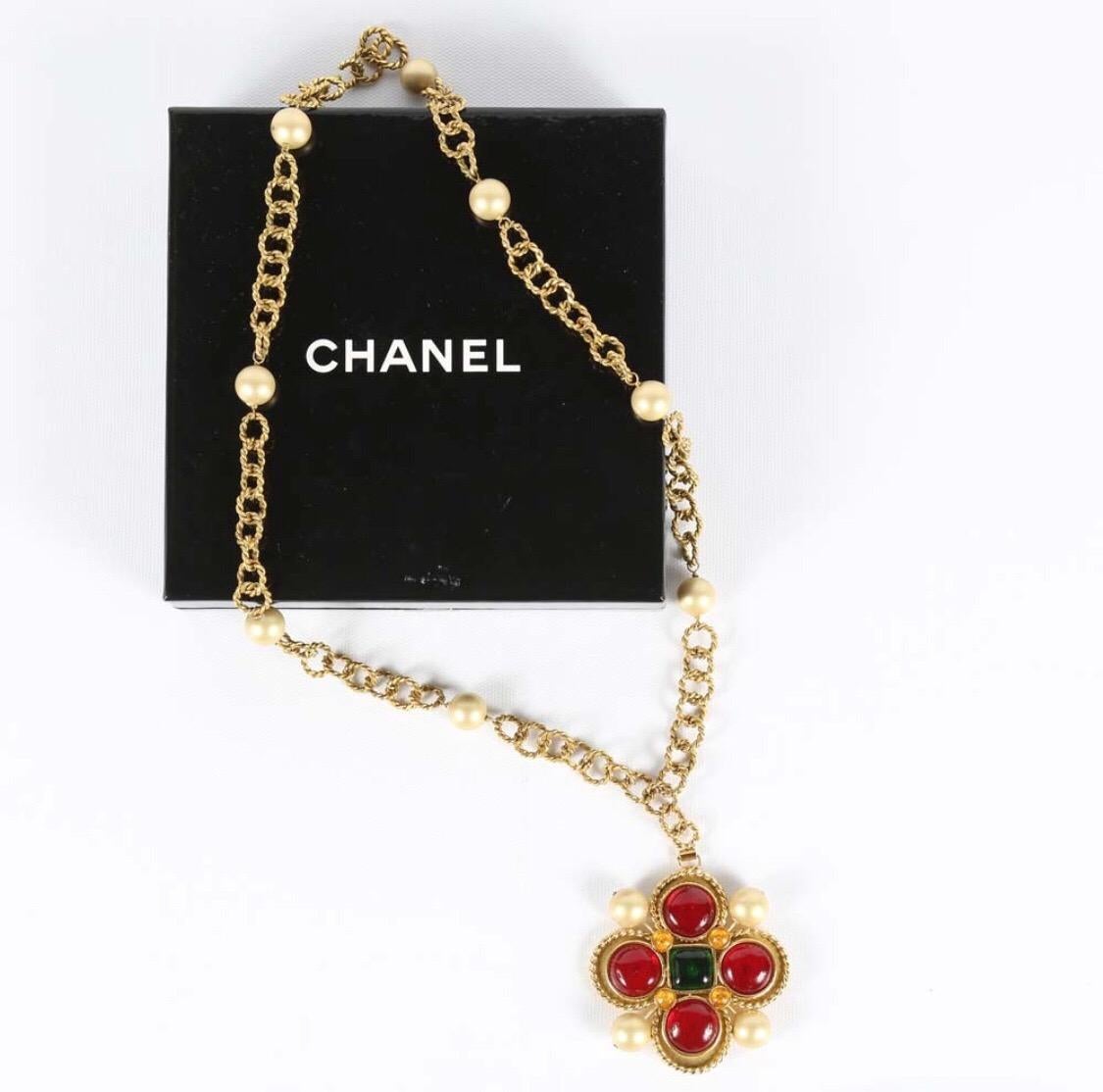A beautiful Chanel Gripoix pendant necklace. This Chanel necklace features a circle linked chain with faux pearls. The pendant is of green gripoix glass center stone is surrounded by multiple red gripoix glass stones and pearls. Marked on the back