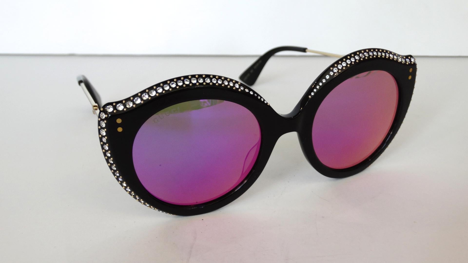 Add some drama to your sunglass collection with our amazing Gucci color shifting cat eye glasses! Black enamel frames in unique oversized cat eye shape, trimmed with crystalline rhinestones all along the edges. Color shifting lenses change from pink