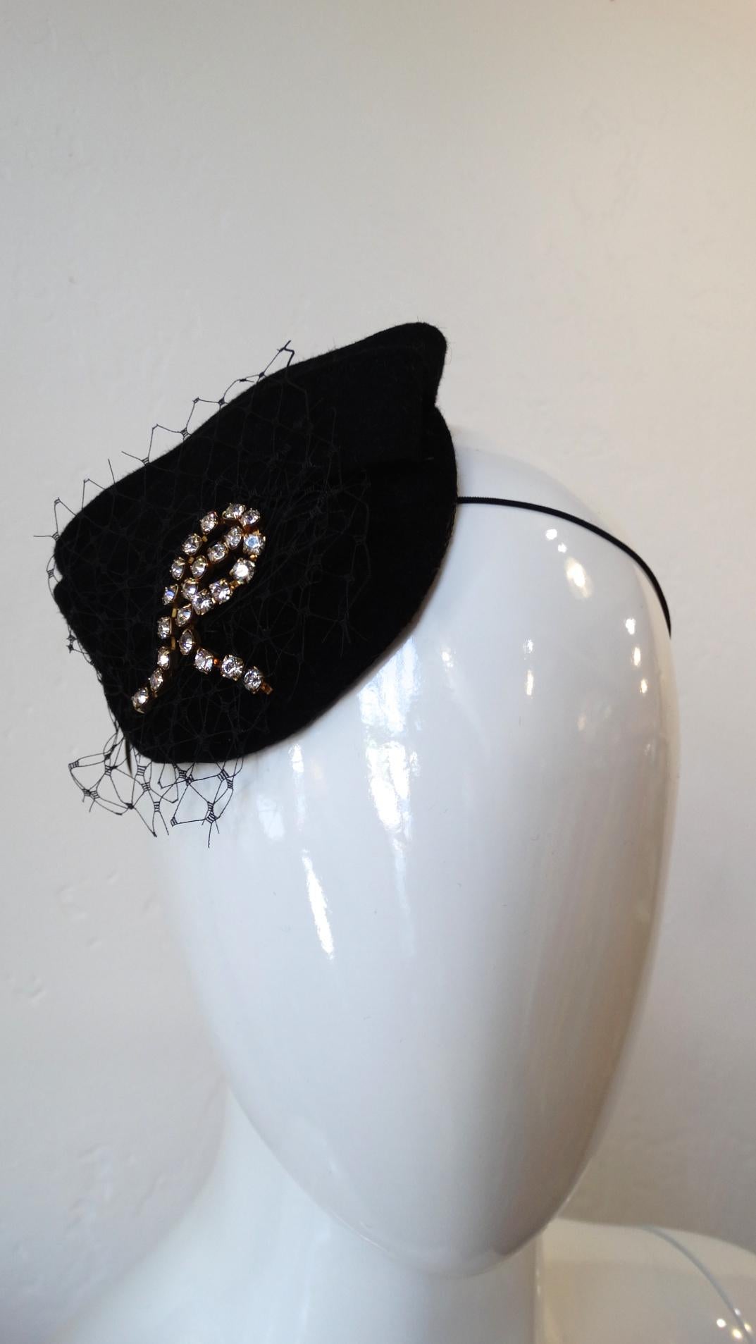 Channel your inner Material girl with our adorable 1980s netted fascinator from hat designer Selima by V! Black fabric abstract shape fascinator with a layer of netting affixed to the base. Rhinestone chain arranged in an 