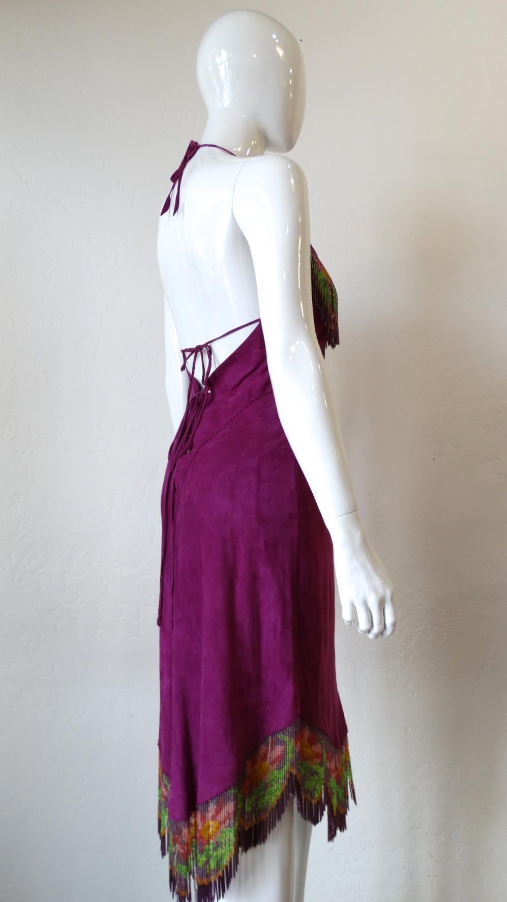 Pretty In Purple! Designed by Clifford Olson Leather, this purple suede bohemian style halter dress is decorated with beaded fringe which displays a floral motif across the top and bottom hem. Turn this number around to find a beautiful lace up tie