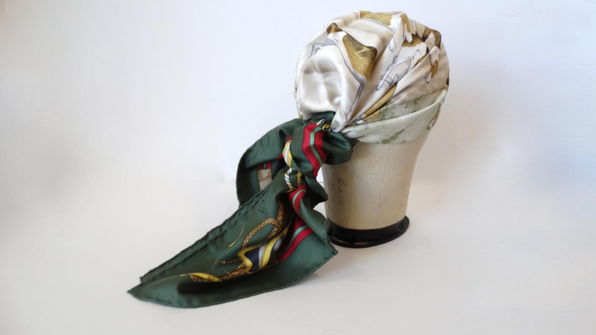 Amazing 1980s Equestrian themed silk scarf from none other than Gucci! Solid white background, decorated by horses and hunting hounds. Bordered by Gucci’s signature contrasting green and red colors. The size of this scarf allows for a number of ways