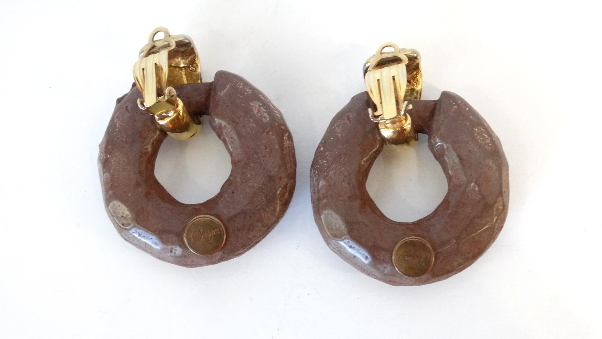 Make A Statement This Fall With These Kalinger Paris Earrings! Hanging off of a textured gold plated clip on closure these hoop earrings, resembling carved wood, are made from a brown resin and features amber colored rhinestones. Signed Kalinger.
