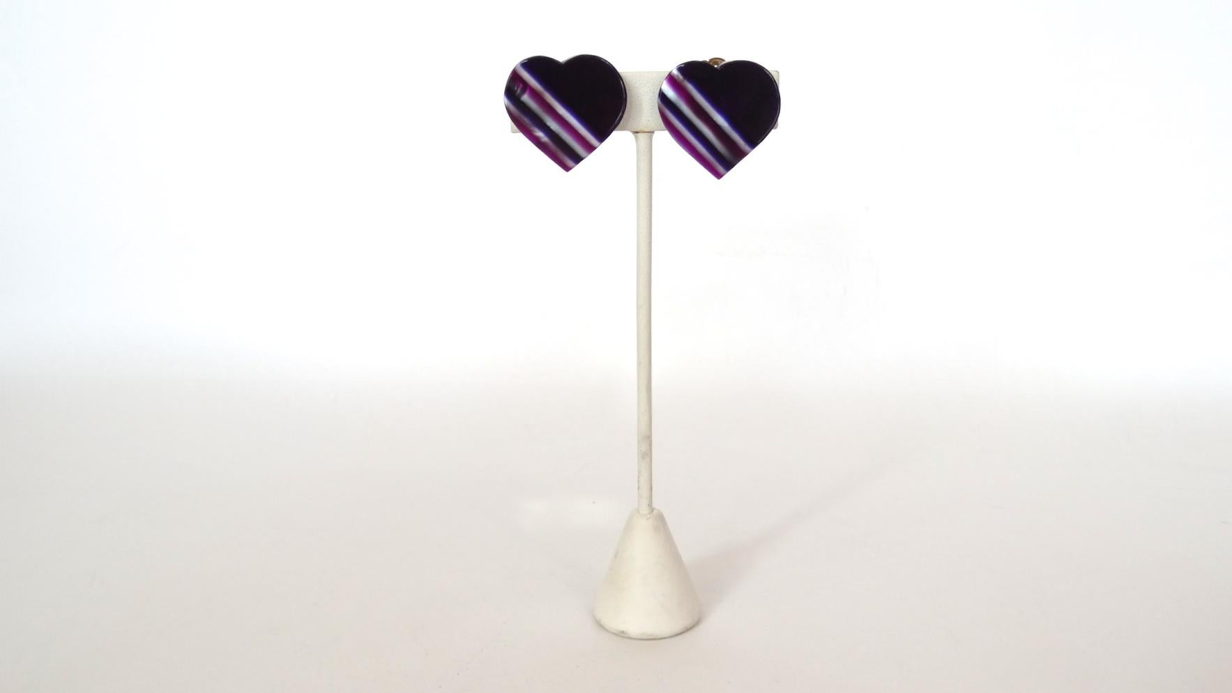How Could You Not Love These Adorable Earrings!? Circa 1970's, these Lea Stein heart shaped earrings feature an asymmetrical pearl white, eggplant and magenta striped design. The perfect earrings to accessorize with any outfit! Clip-on closures,