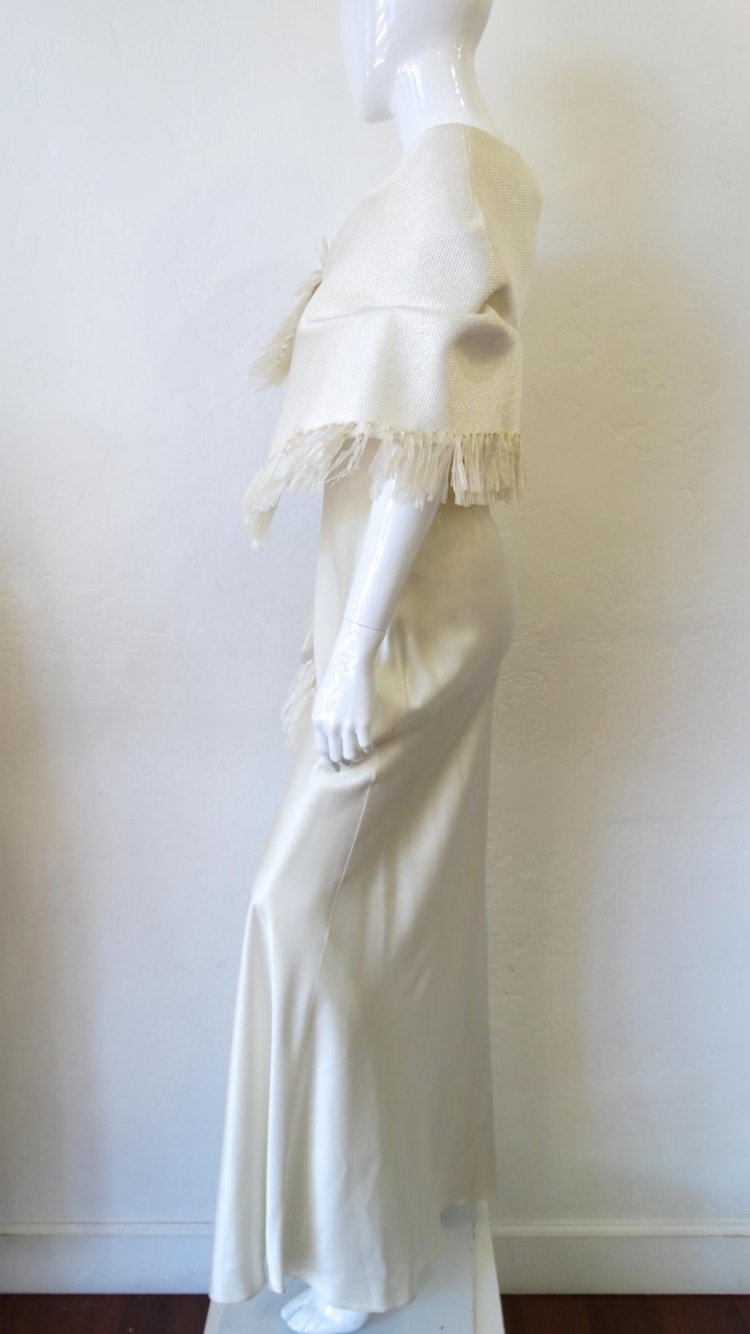 All Eyes Will Be On You In This John Galliano Dress! Circa 1990s, this floor length dress is a gorgeous soft creamy white color and flows effortlessly. Features an elegant square neck and is decorated with raffia accents on the inside trim which