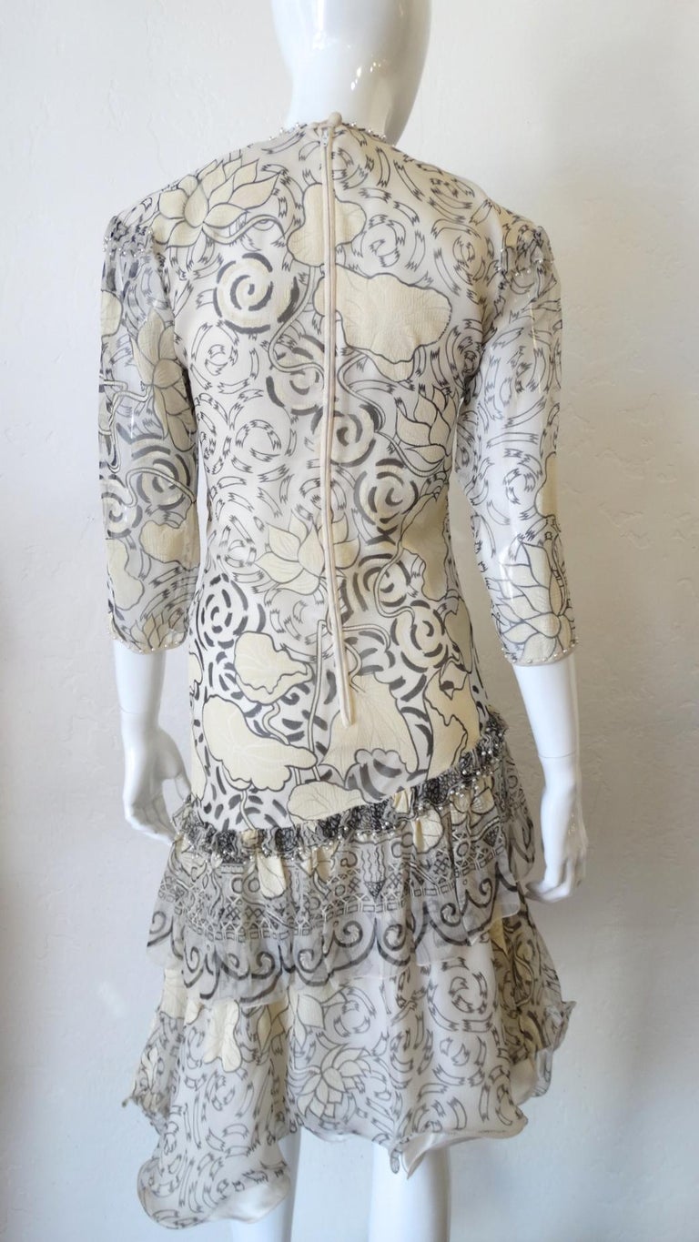 Looking For The Perfect 80s Dress? Well It's Arrived! Circa 1980s, this Zandra Rhodes asymmetrical drop waist dress features a cream and black pattern of flowers, swirls and tribal inspired designs at the top tier ruffled hem. Beads and pearls are