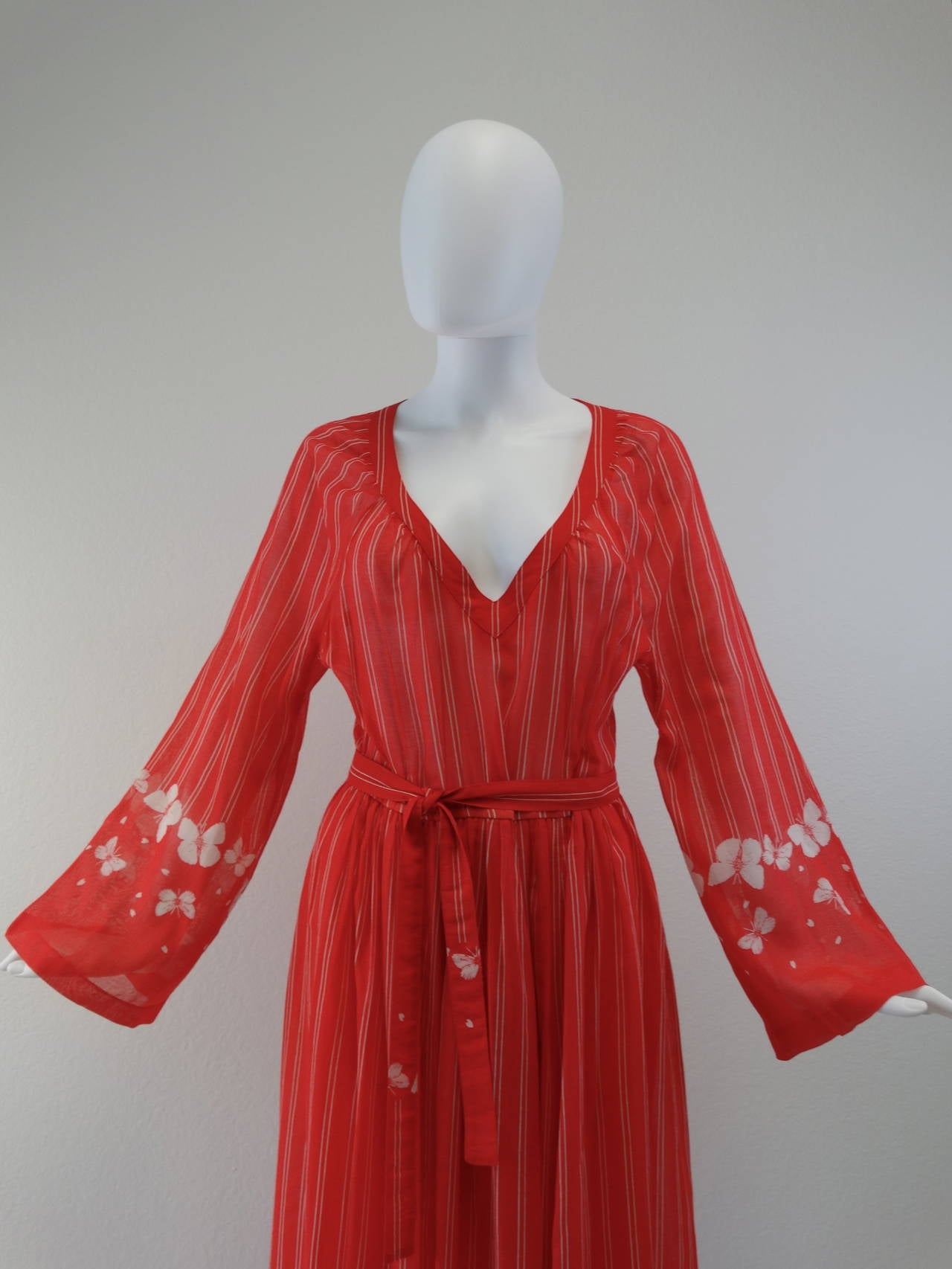 Featured is a lovely late 1970s Hanae Mori cotton maxi dress with a v-neck neckline. Its whimsical butterfly design trims the bottom of the sleeves and dress hem with white stripes covering the entire surface. It is made of a light cotton and has a