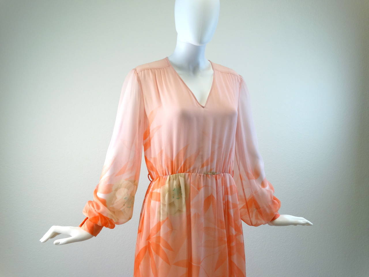 Beautiful Hanae Mori vintage 80's silk maxi gown. Soft nude, peach with beautiful pink and green flowers that makes for a 3-D effect. Long billowing sheer sleeves, with double snap closures. This piece does have two belt loops but no belt. You could