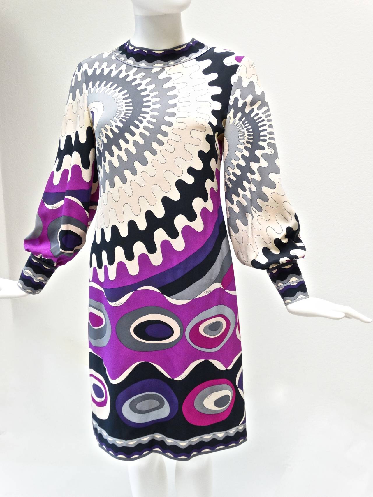 Fantastic 1960’s Pucci long sleeve dress is made from silk crepe chiffon printed with an iconic psychedelic graphic in shades of violet, fuchsia, grey, black, beige  and white. Dress sleeves are banded with 3 small snap buttons.  Dress has a metal
