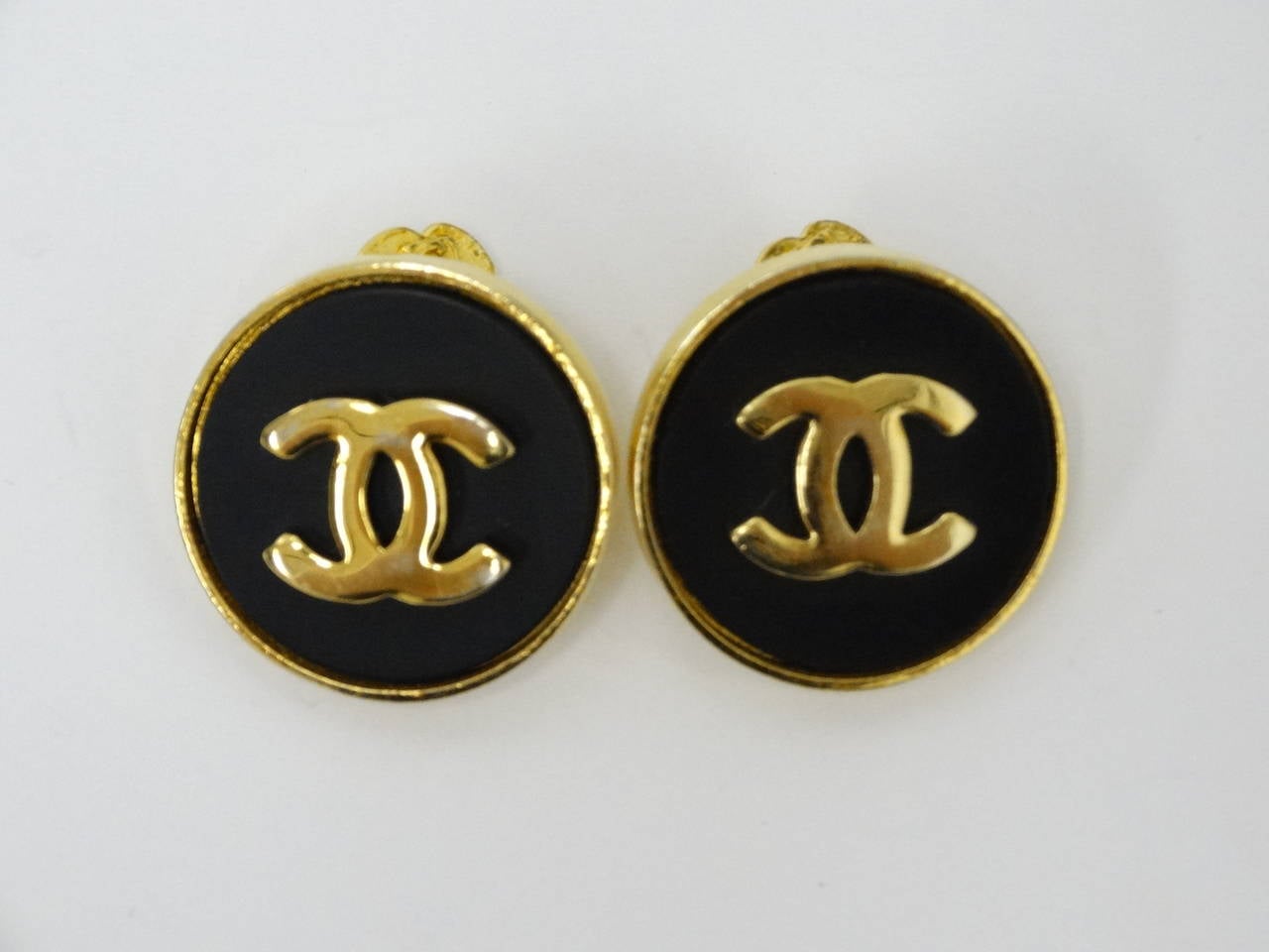 Add a touch of sophisticated flare to your professional attire/street style with this superb set of Chanel cuff links! They're fashioned from gold tone metal and black acrylic with signature C's and fasten with a Camelia flower toggle. Signed Chanel