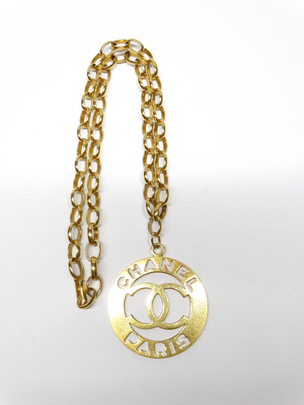 Make a statement with this lovely Chanel gold tone Extra Large Medallion Necklace, Circa 1970's! CHANEL PARIS and the CC logo cut out from the metal affixed on a gold link chain with adjustable hook closure, stamped Chanel.

The gold plating is