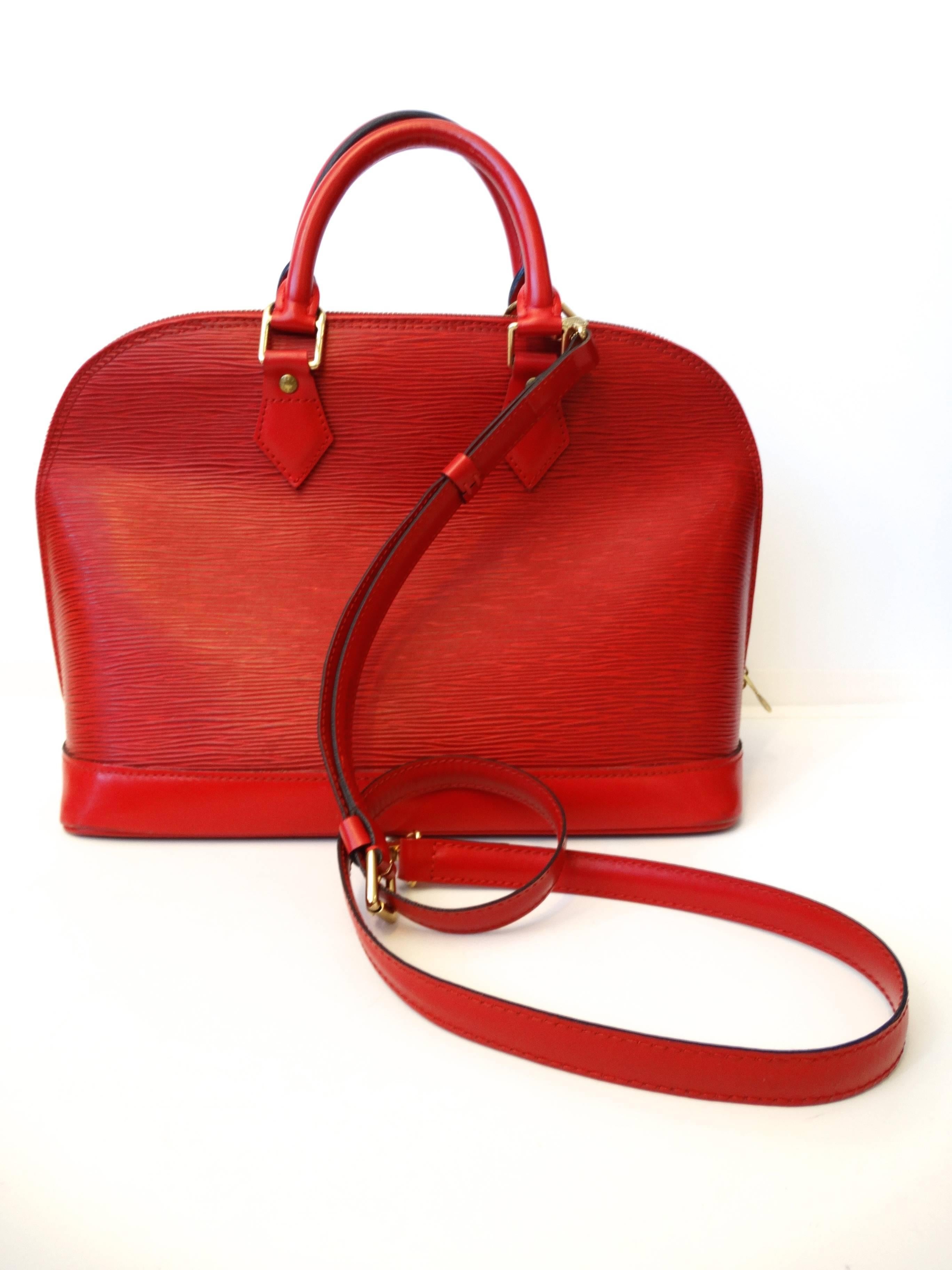 LOUIS VUITTON Vintage Epi Alma PM in Castilian Red. This is a stunning bowler style tote that is created out of Louis Vuitton signature textured epi leather in red. The bag features strong cowhide rolled leather handles and trim with brass hardware