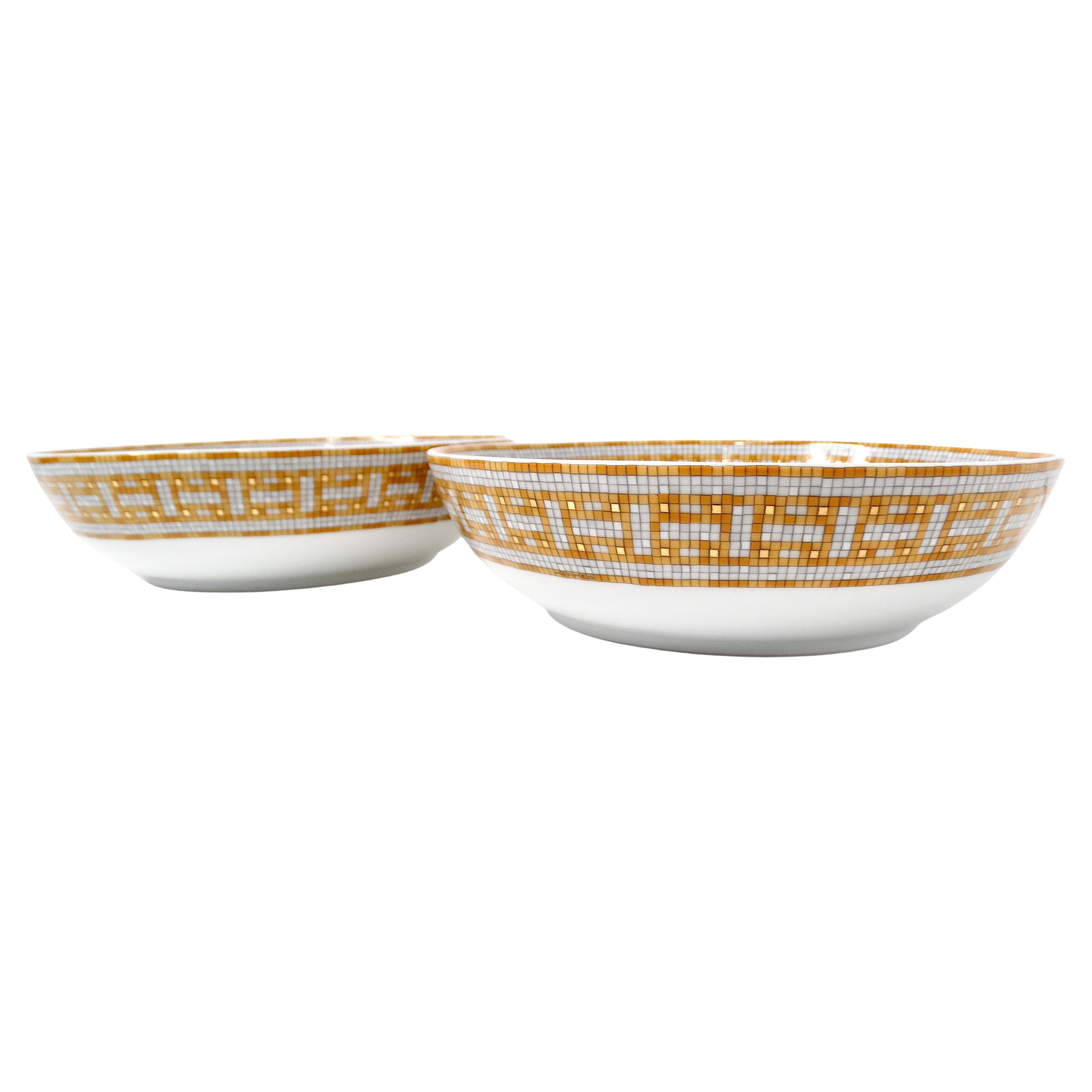 Das Hermes Mosaique au 24 Van Quatre Gold Porcelain Bowl 2er-Set ist ein Beispiel für exquisite Handwerkskunst und luxuriöses Design. Mit ihrem lebhaften Mosaikdruck in Gelb-, Orange- und Weißtönen und den schimmernden Goldakzenten sind diese