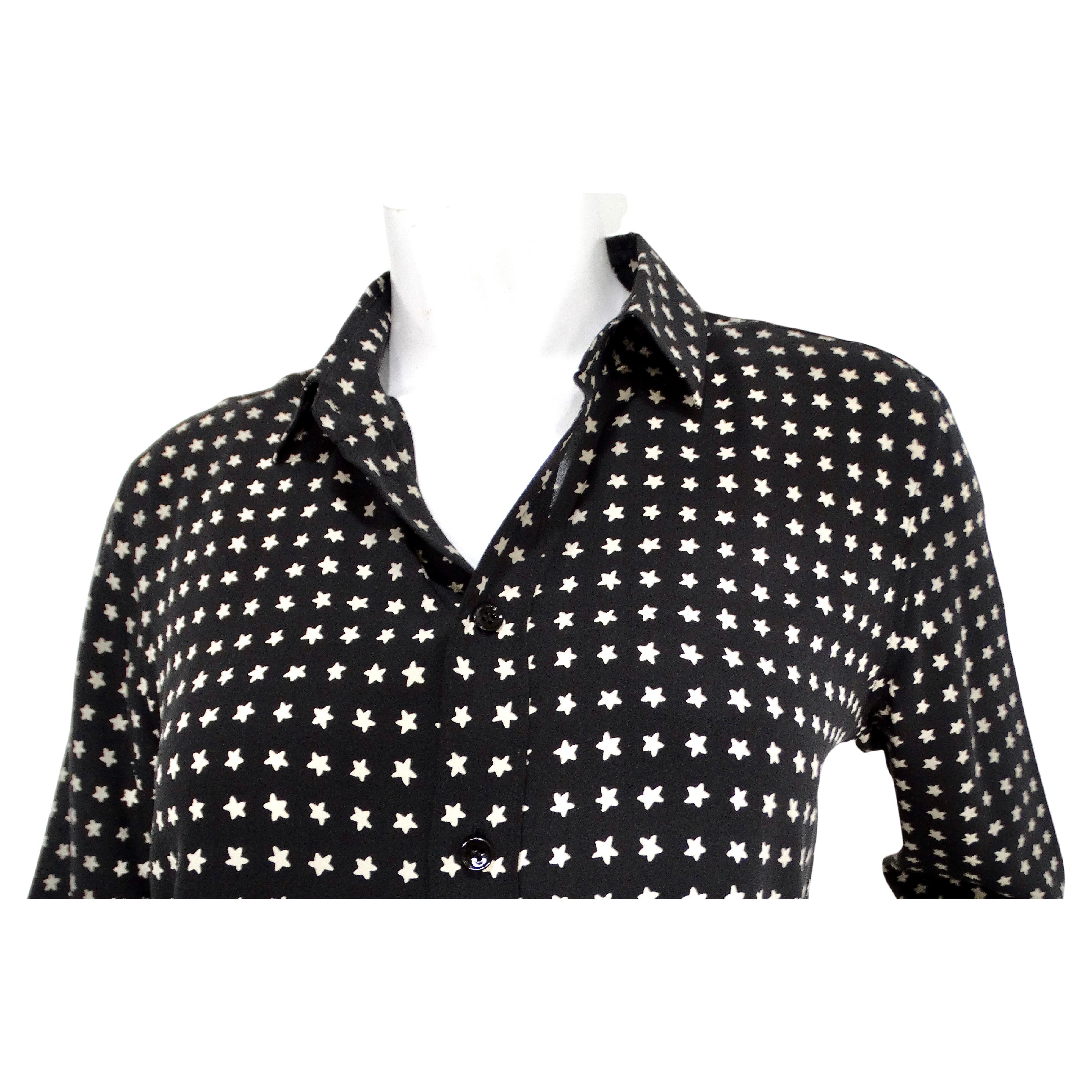 La blouse boutonnée à manches longues en soie imprimée d'étoiles noires et blanches de Saint Laurent est une pièce remarquable qui allie magistralement l'élégance classique à une touche de motif ludique. Confectionnée en soie luxueuse, cette blouse