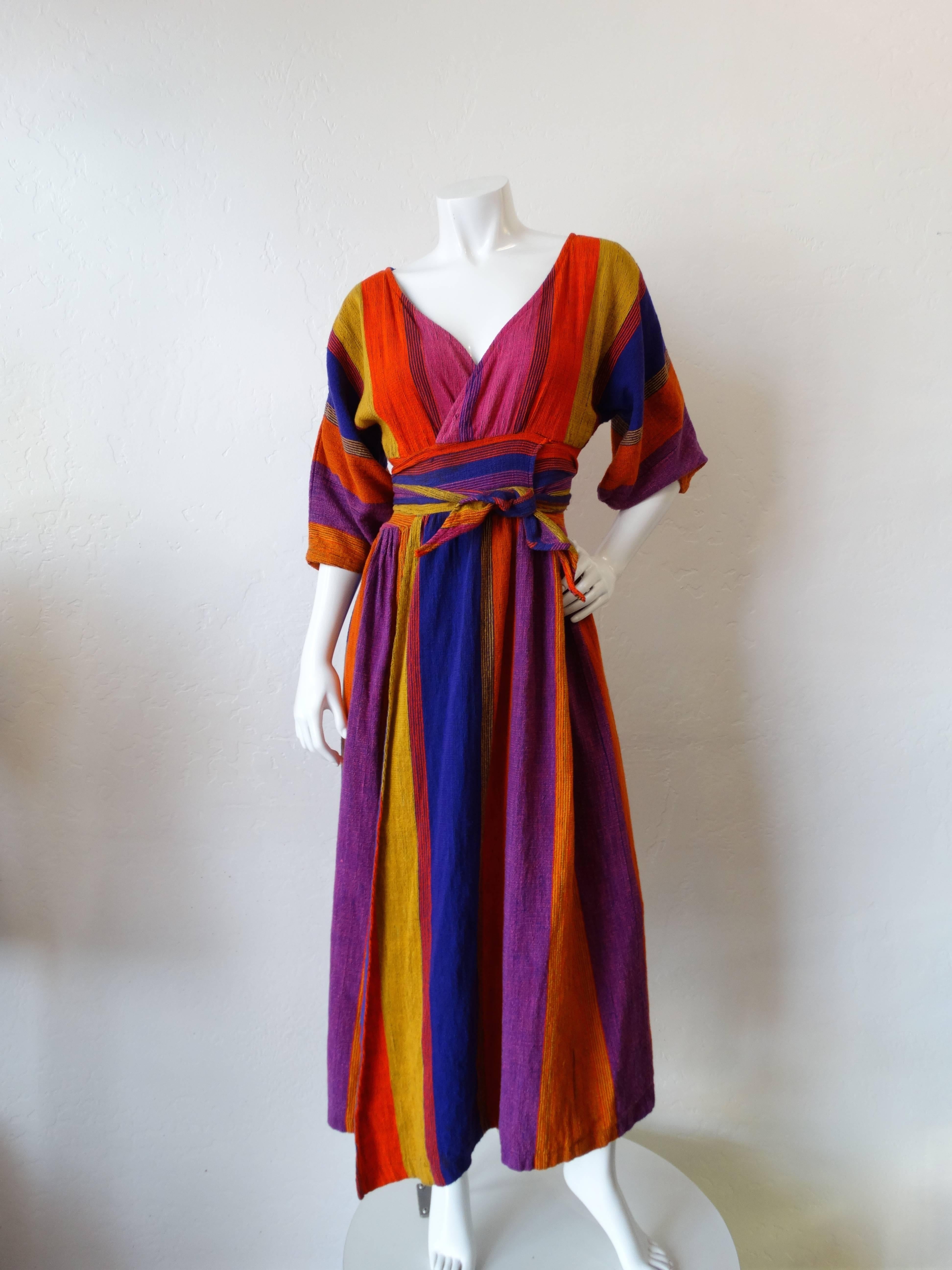 Incredible 1970s Rikma dress imported straight from Israel! Striped, woven cotton fabric in brilliant hues of violet, orange, pink and yellow! Short, bell-like sleeves with slits at the tops of the shoulders. Wrap dress silhouette, ties around the