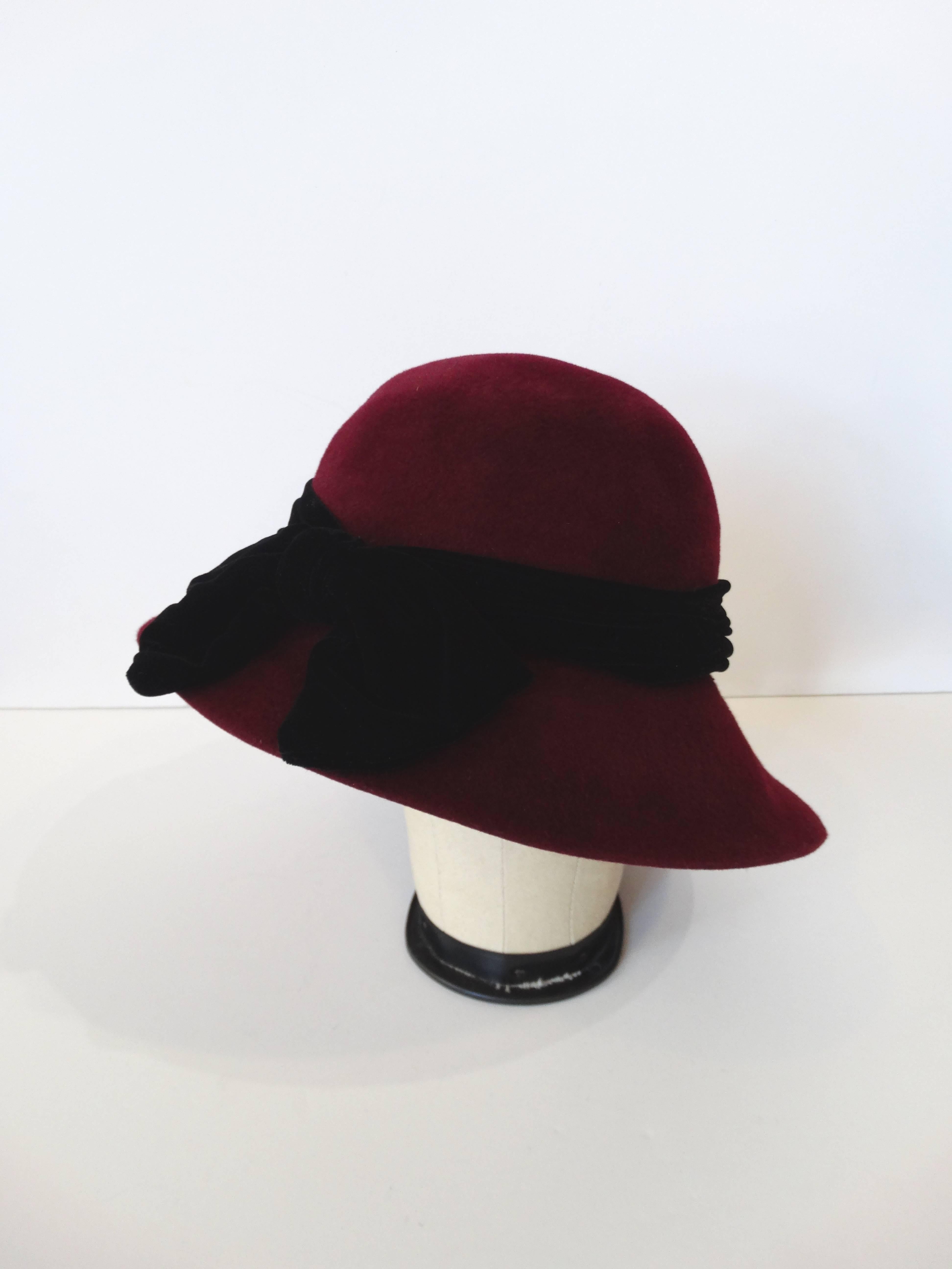 She's style, she's class and she's wearing a YSL hat! Dress to the nines in our 1960s Yves Saint Laurent cloche hat! Classic cloche silhouette with slightly exaggerated brim. Accented with oversized black velveteen bow and trim around the perimeter.