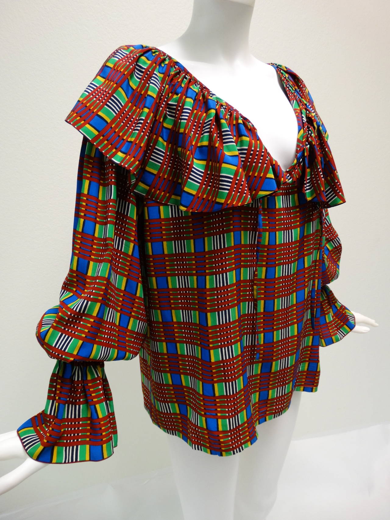 Vintage Yves Saint Laurent maroon, bright green, royal blue, black, white and gold raw silk peasant sleeve blouse featuring an all over plaid print. Ties at the neckline, trimmed with a large ruffle  and micro pleating. Size 40 EU = 4/ 6 US