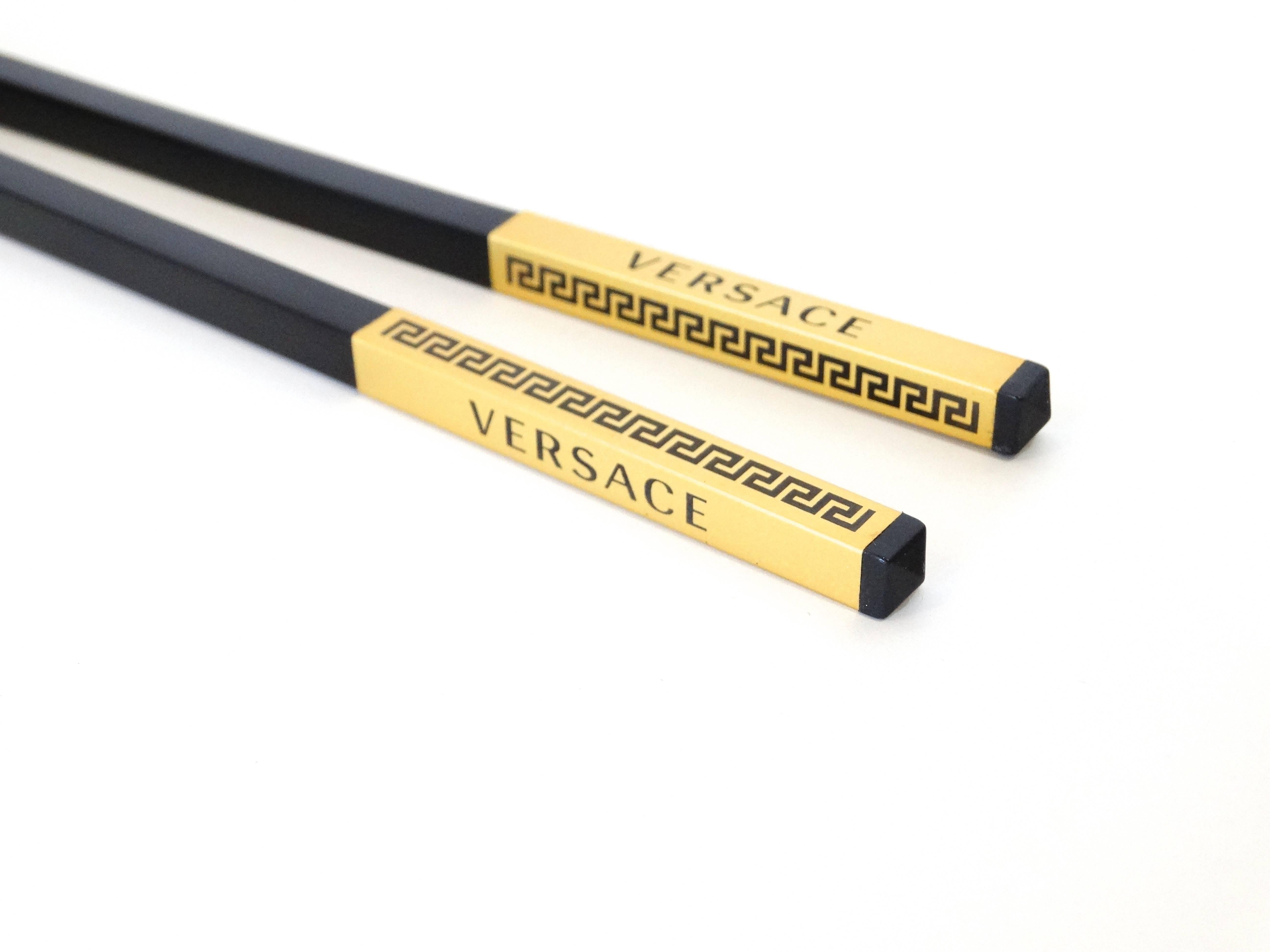 A fabulous set of Versace hair sticks (also chopsticks) a beautiful matte black color with the signature Greek key design in 24kt gold paint Versace logo, these sticks are straight with a slight pointed end. Nine inches in length, use to hold a