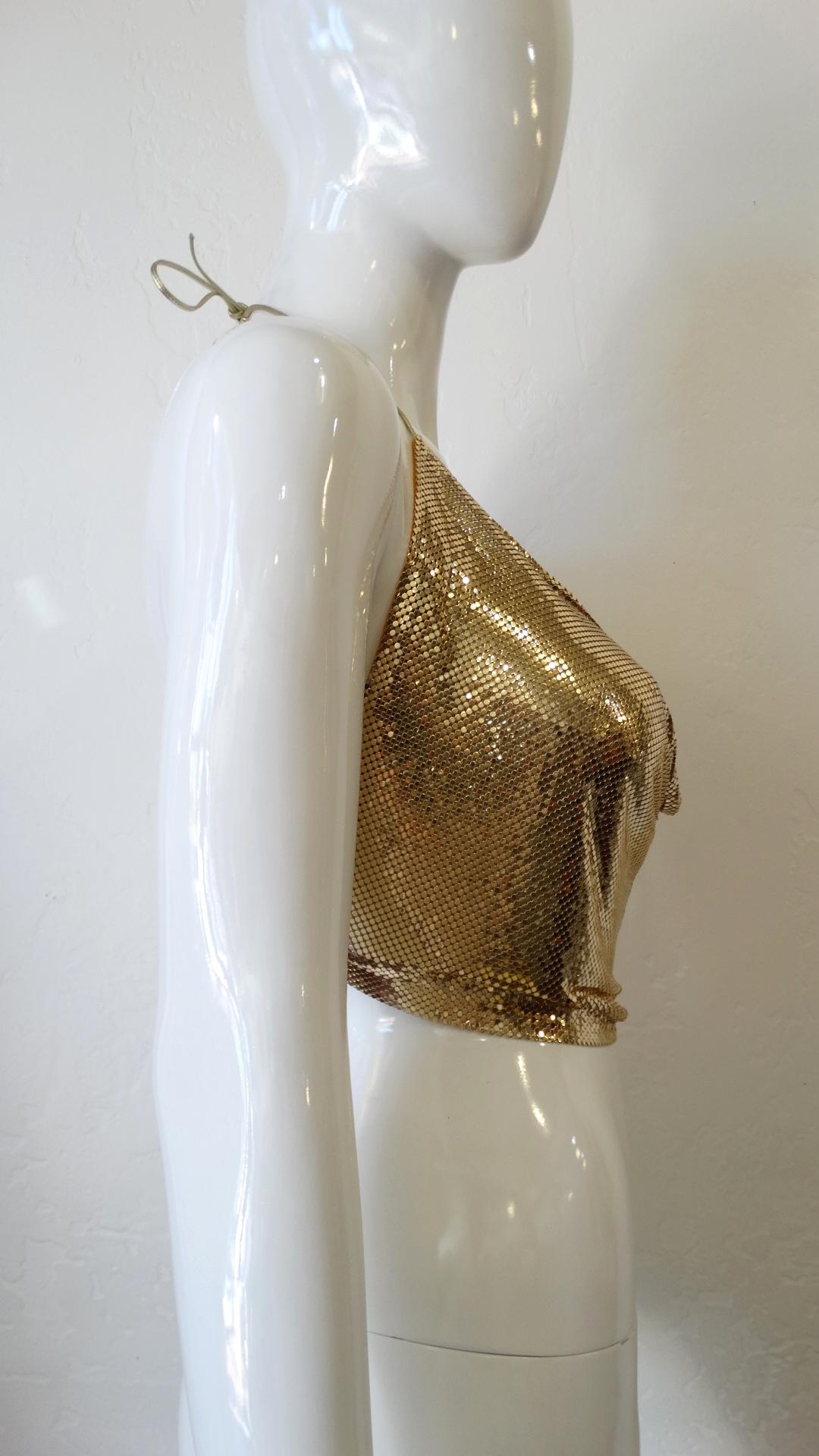 Bring The 70s Back With This Metal Mesh Backless Halter Top! By Whiting and Davis, this crop top features a gorgeous gold color. Includes metallic gold ties to the halter neck and to the back at the waist, with a draped neckline. The perfect top for