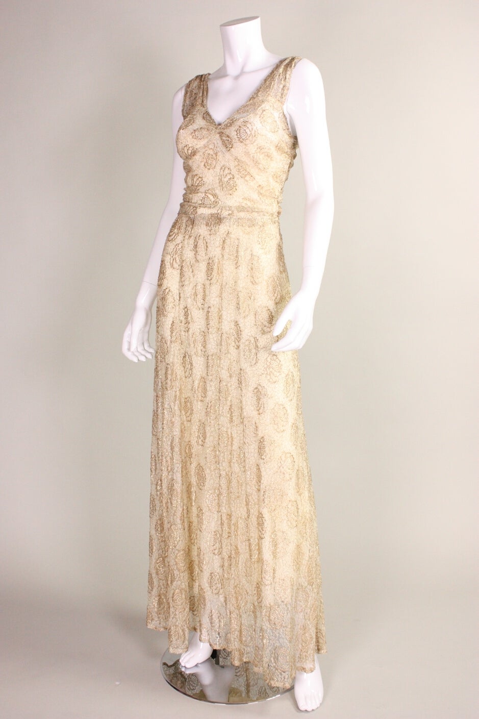 Vintage gown dates to the 1930's and is made of ivory lace woven with metallic gold lamé in a floral motif.  Shoulders and center front bust are gathered.  V-neck.  Side snap and hook and eye closures.  Unlined, but comes with a bias-cut slip.

No