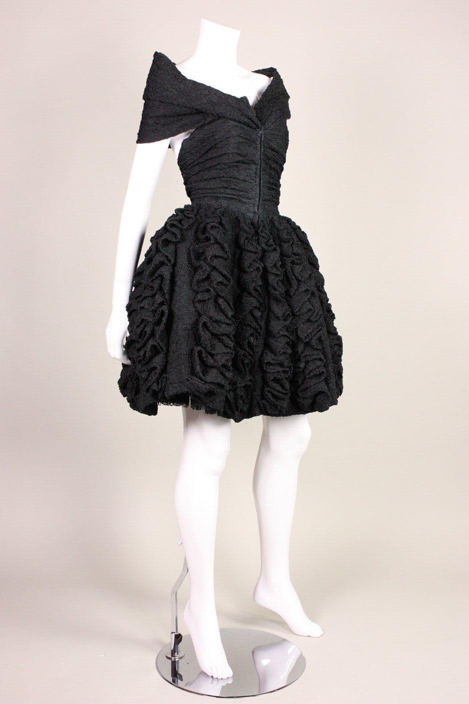 Vintage cocktail dress from Christian Lacroix dates to the 1990's and is made of crinkled black silk.  Boned bodice has horizontal ruching and fabric attached at the center front bust that creates a shawl-like collar that sits just off of the
