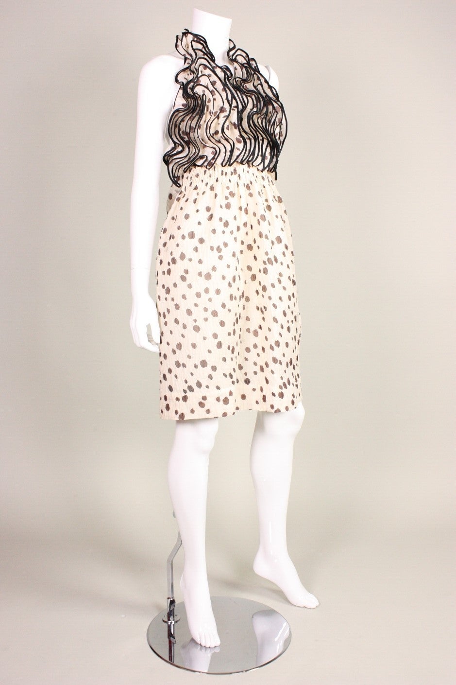 Adorable cocktail dress from James Galanos is made of cream fabric with brown dots.  Fitted bodice is covered entirely with vertical ruffles.  Knee-length skirt.  Halter neckline.  Three-dimensional flower at lower back.  Center back zippered