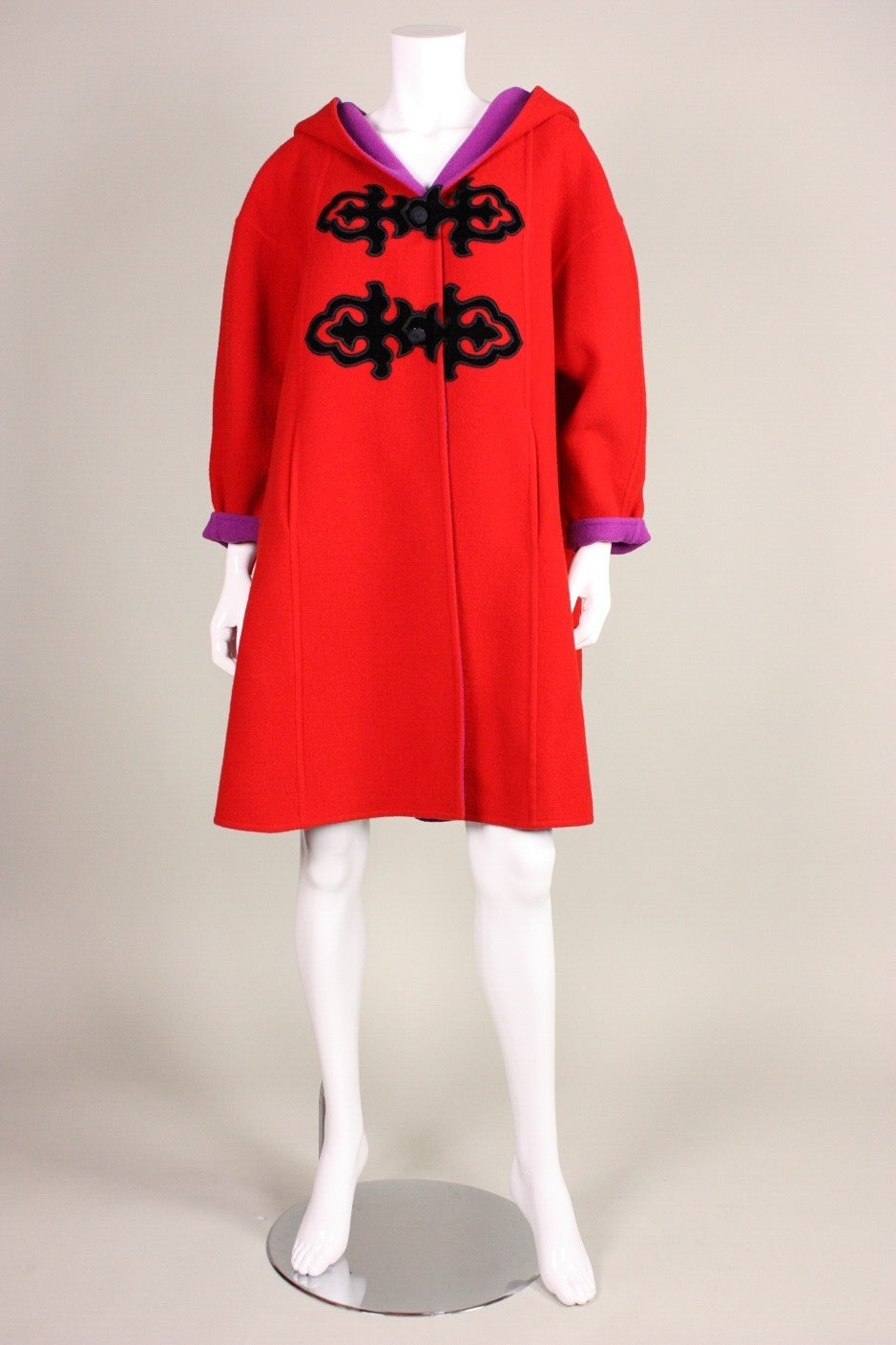 Christian Lacroix coat dates to the 1990's and is made of bright red wool with black velvet appliques.  Drop shoulder.  Tapered sleeves.  Center front snap closures.  Bright magenta wool lining.  Hip pockets.

Labeled size 36, but could