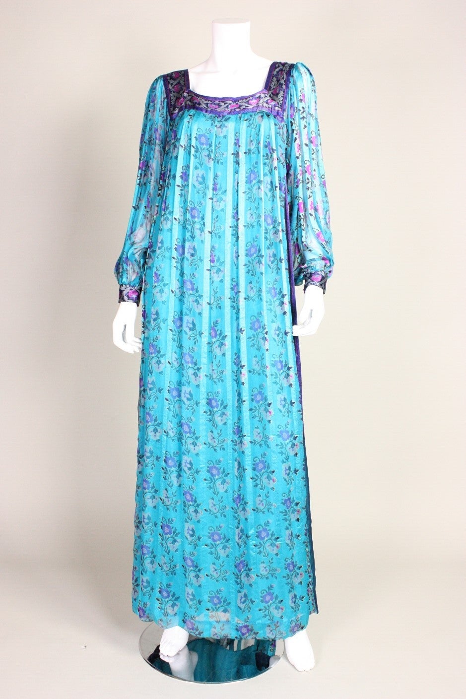 Vintage maxi dress from Raksha dates to the 1970's and is made of printed turquoise silk chiffon. Squared scoop neckline. Long sleeves button at the cuffs. Lined except for in sleeves. Center back zipper.

Labeled size