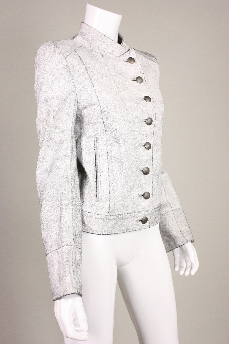 Military-inspired jacket from Ann Demeulemeester is made of textured leather with a crackle finish.  Stand collar.  Diagonal button closure with silver-toned buttons.  Fully lined.

Labeled size 36.

Measurements-
Bust: 34