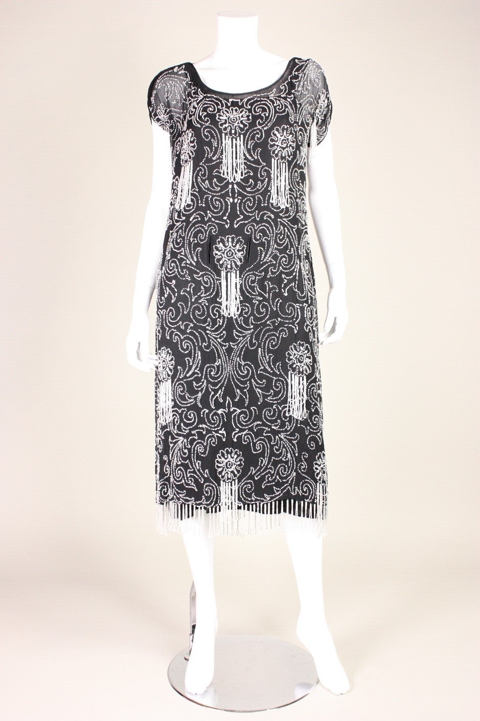 Vintage dress dates to the 1920's during the Art Deco era.  It is made of black silk chiffon with pearly white bugle beads sewn throughout in a scrolling pattern.  Beaded fringe throughout dress and at the hem.  Unlined, but comes with a black slip
