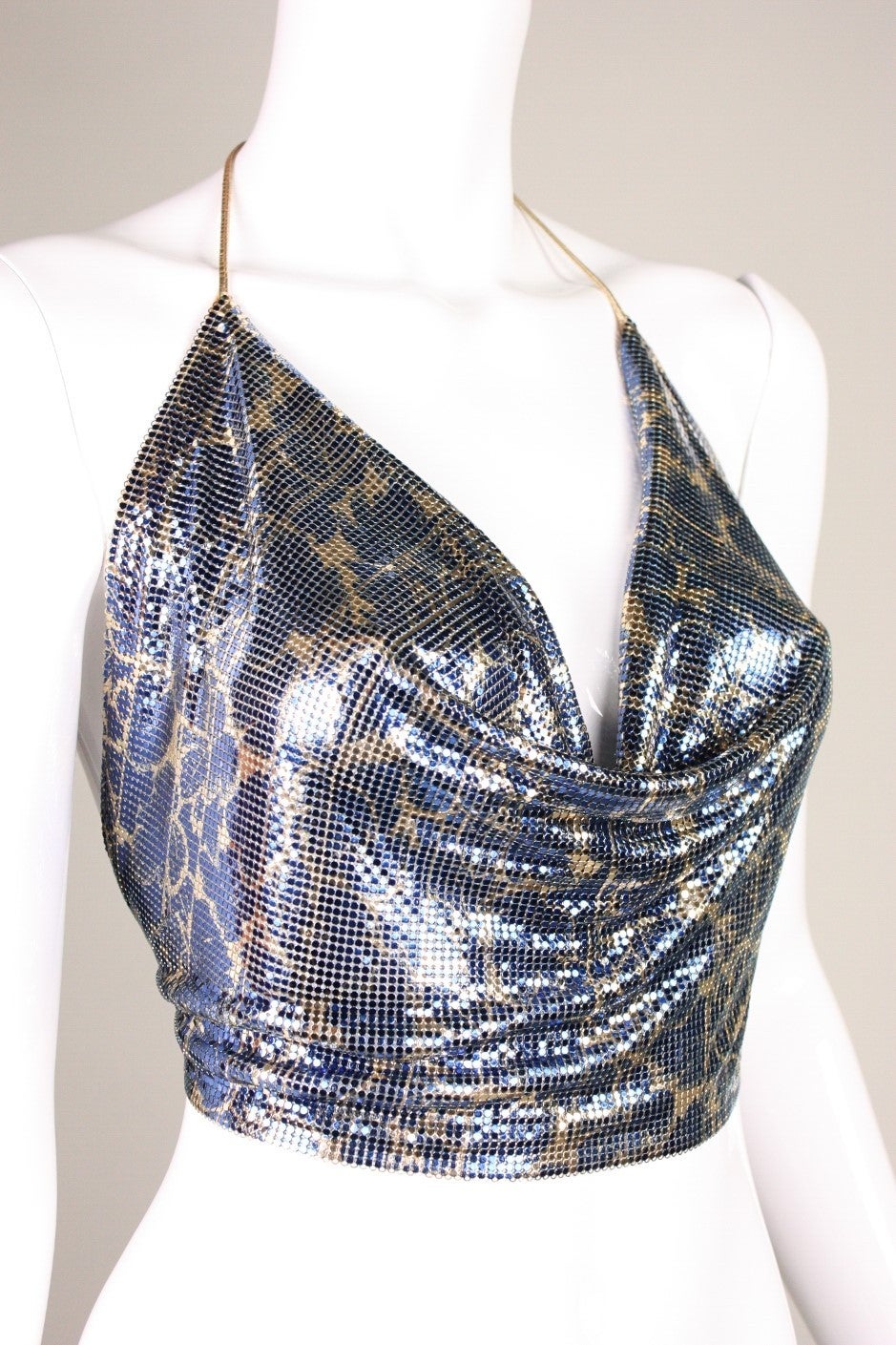 Vintage halter top from Whiting & Davis is made of printed gold and blue metal mesh.  Gold leather ties at neckline and waist.  Mesh drapes beautifully into a cowl neckline.  Unlined.

No size label, but we believe it is an open size; however, the