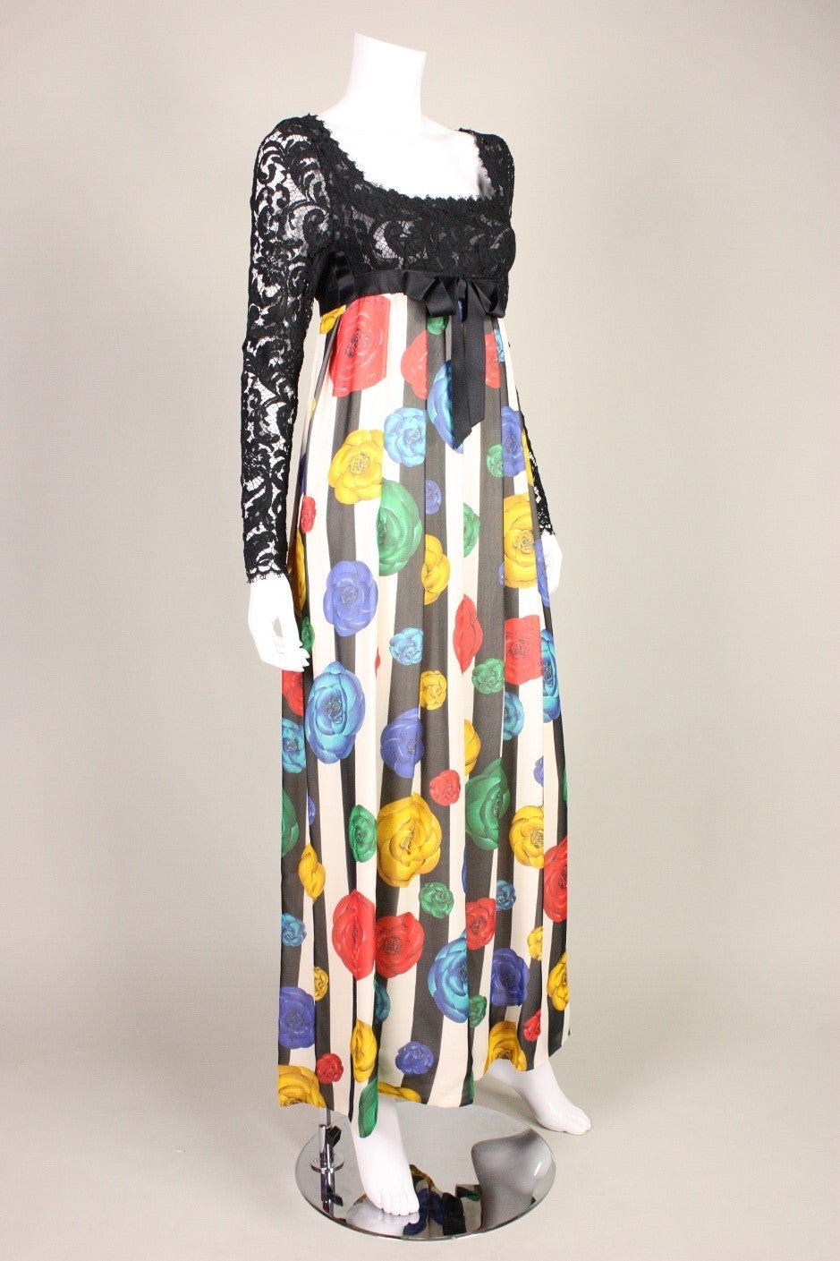 Vintage gown was designed by Karl Lagerfeld for Chanel in the early 1990's.  Long-sleeved bodice is made of black lace and has a squared neckline with a scalloped edge.  Signature multi-colored camellia print skirt also has a striped print.  Satin