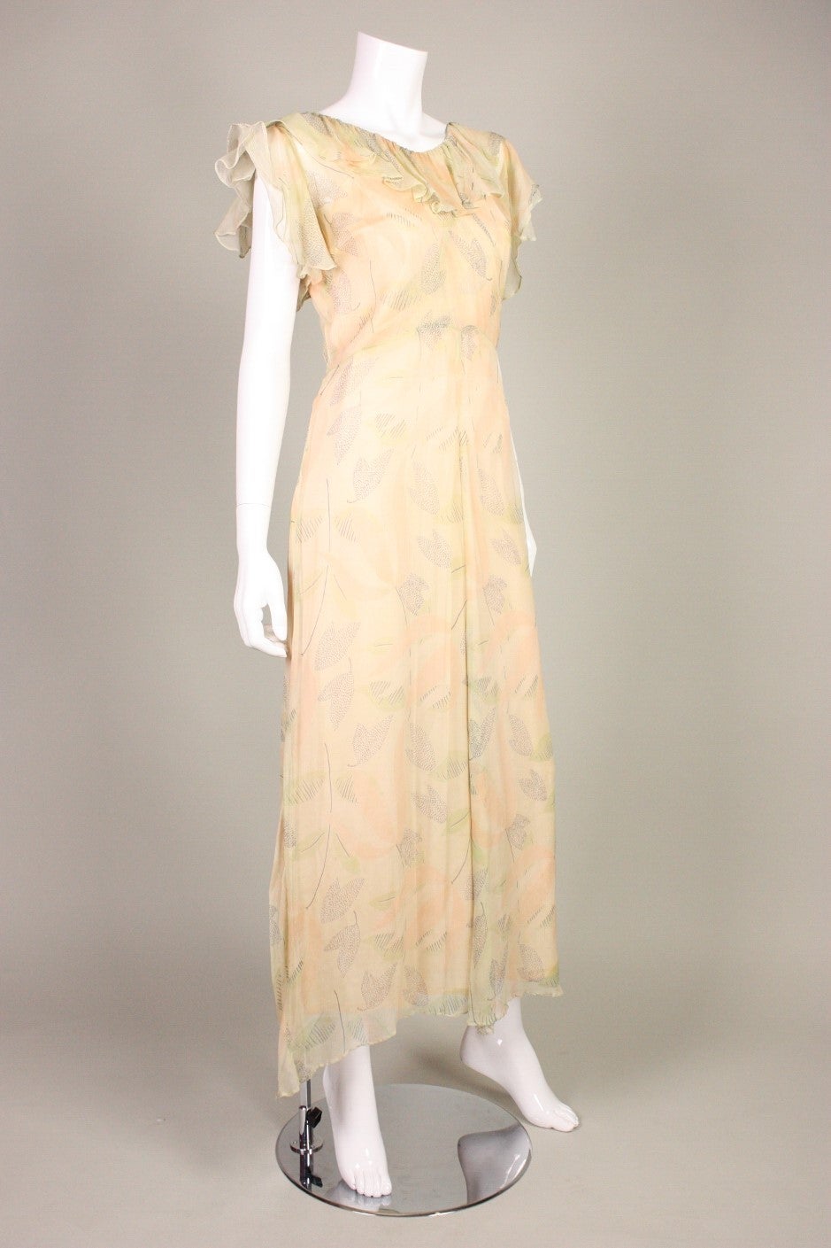 Vintage dress dates to the 1930's and features an Art Deco geometric floral print.  It is made of peach chiffon with a ruffled neckline and flounce sleeve with organza to stiffen.  Side snap closure.  Unlined, but comes with a slip of a similar