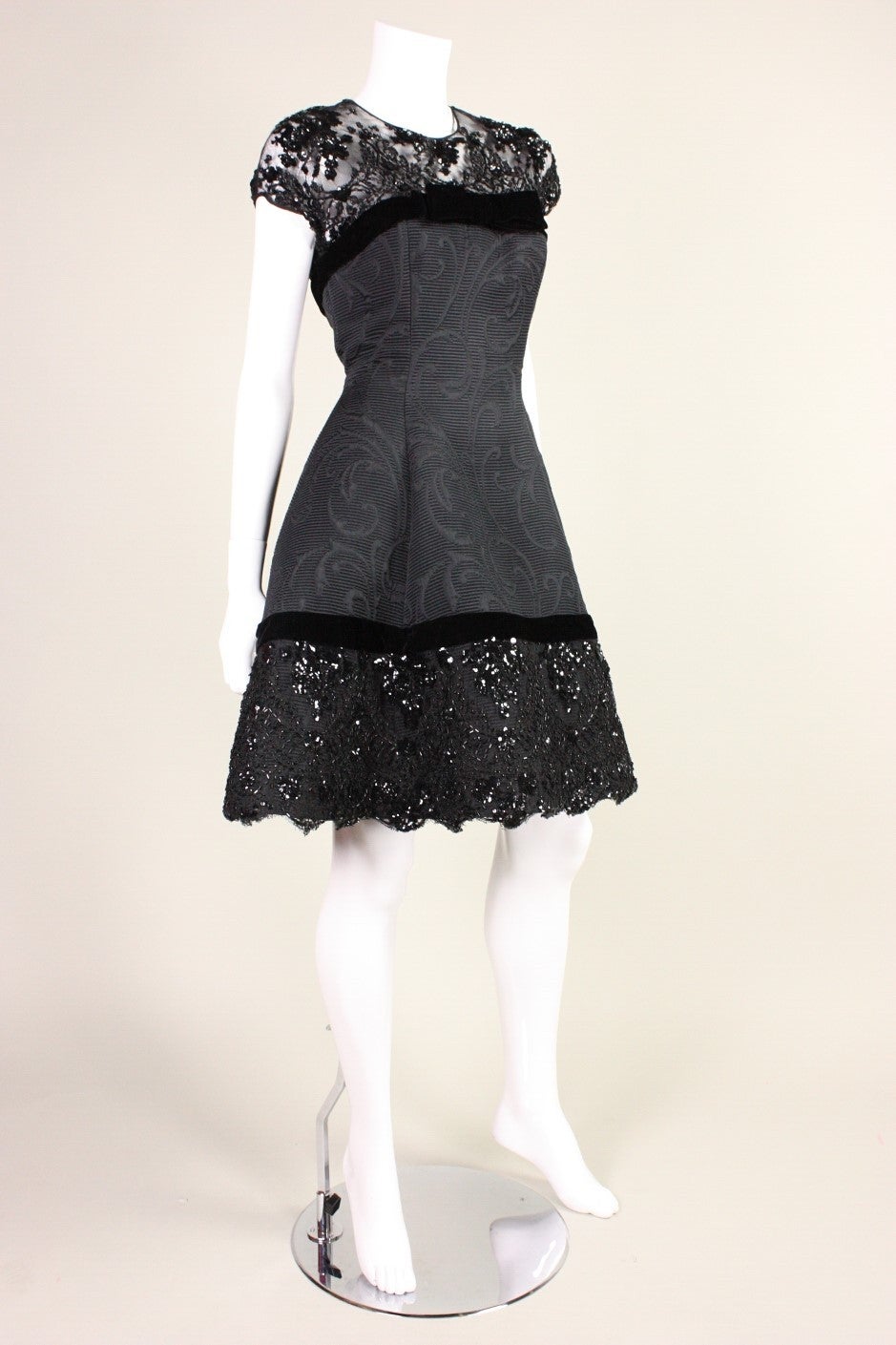 Lovely cocktail dress from Oscar de la Renta likely dates to the 1990's and is made of a mixture of black silk jacquard, black beaded lace, and velvet.  Bodice is fitted with a round neckline and cap sleeves.  Full skirt has a stiff underskirt for