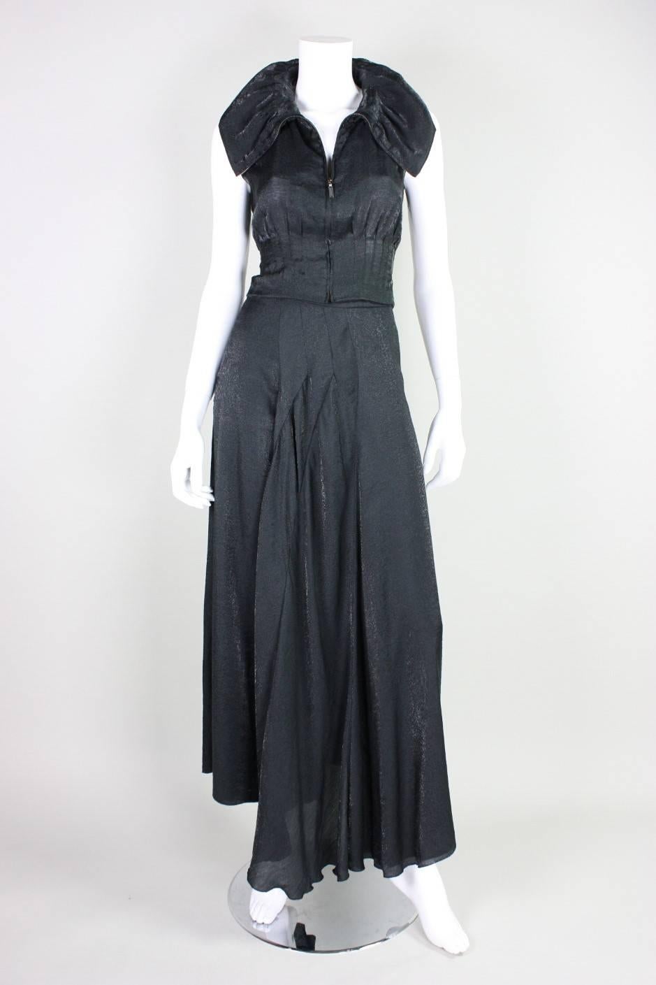 1999 ensemble from Chanel by Karl Lagerfeld is made of a black rayon blend with a muted snakeskin print.  Sleeveless bodice has vertical pleats all around waistline and portrait collar.  Ankle-length skirt has interesting seaming that creates volume